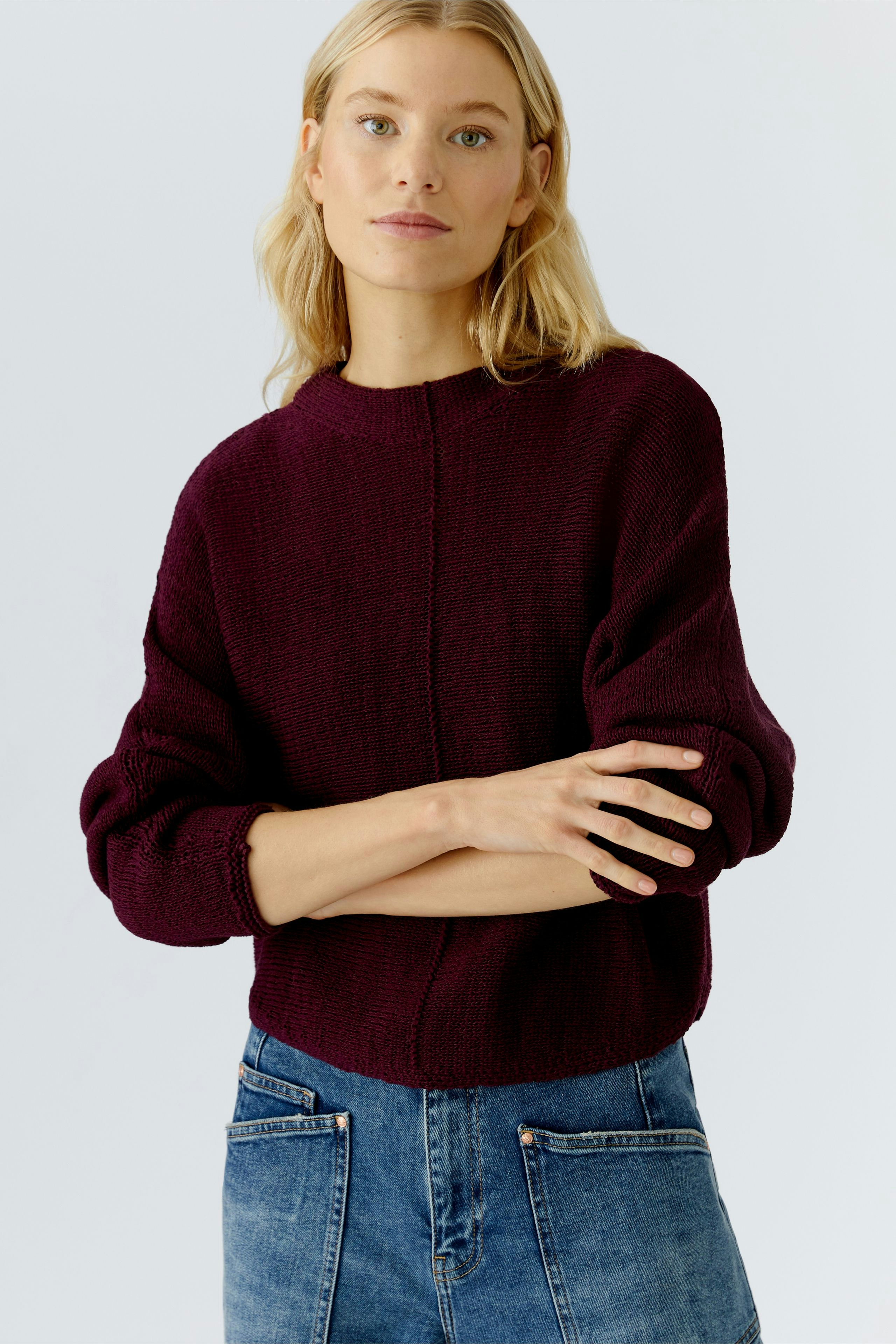 Damen-Pullover: Junge Frau in bordeauxfarbenem Strickpullover mit lässigem Schnitt und lockeren Ärmeln.