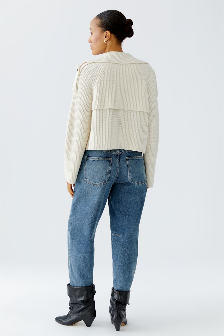 Damen-Strickjacke: Frau in heller, kurzer Strickjacke mit lässigem Schnitt und Jeans.