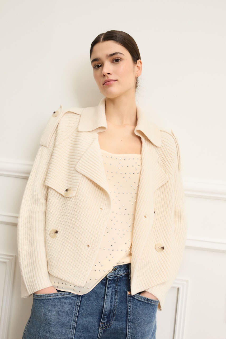 Moderne Damen-Strickjacke: Frau in beiger Strickjacke mit lässigem Top und Jeans.