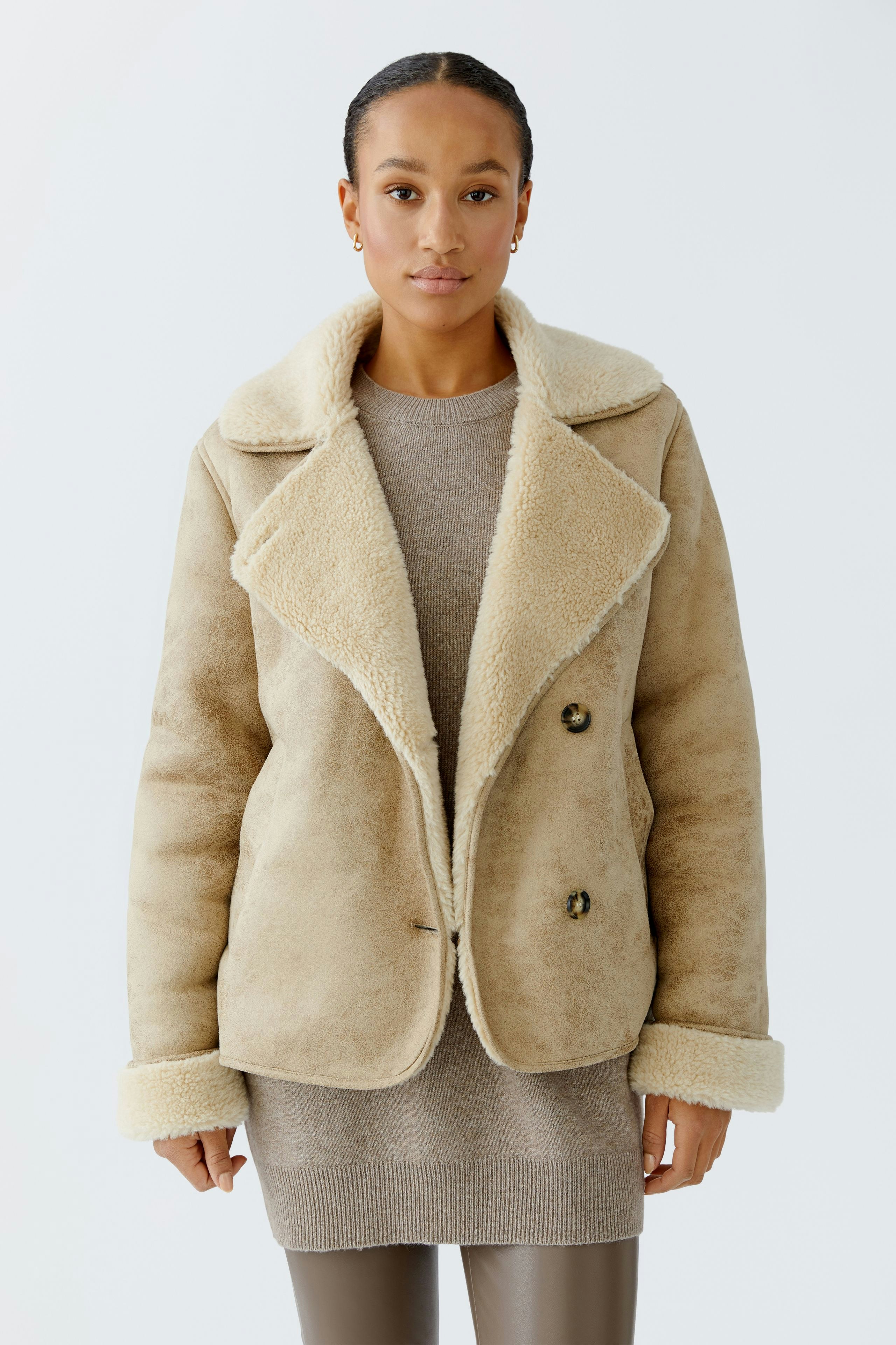 Casual women's outdoor jacket: A woman in a beige jacket with a soft collar and buttons, styled with a sweater.