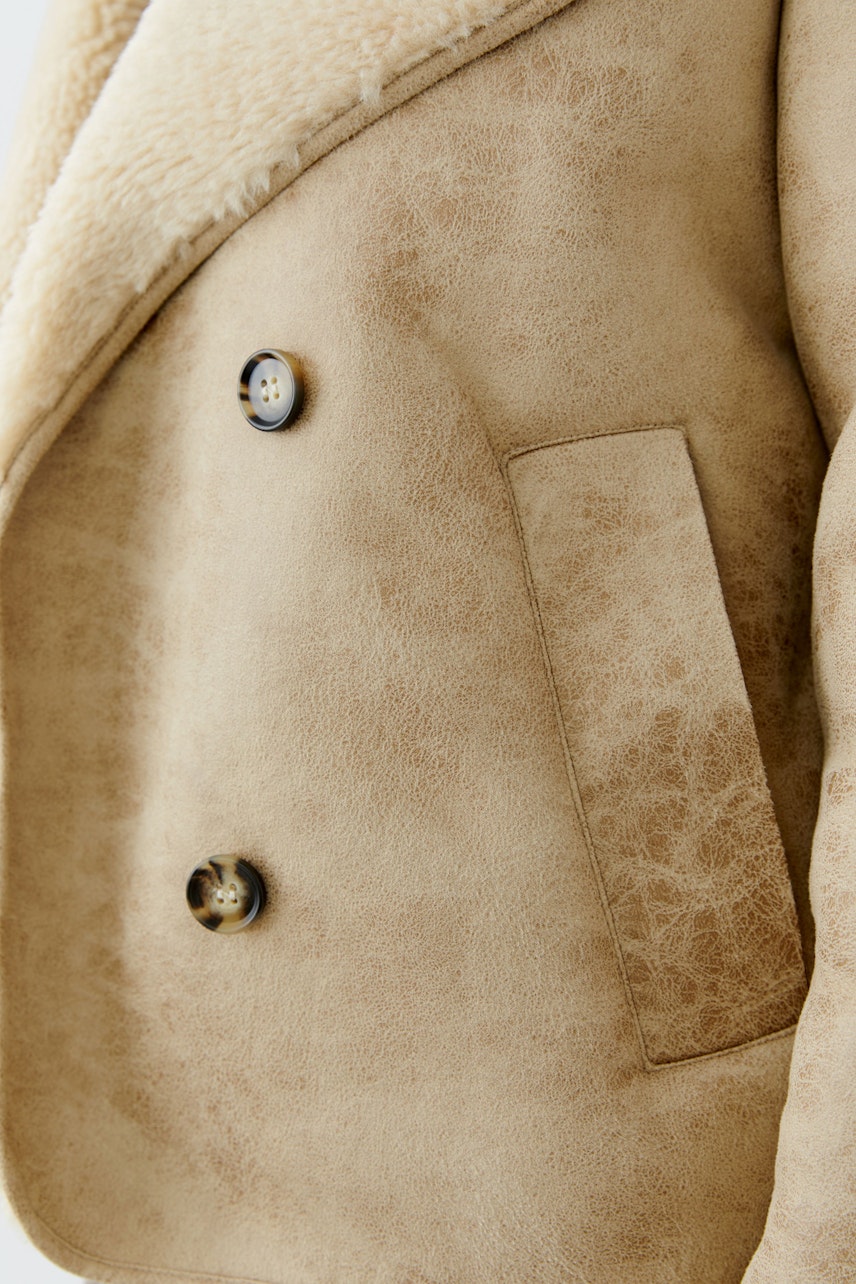 Beige Outdoorjacke: Detailaufnahme einer Damenjacke mit Knöpfen und Taschen.