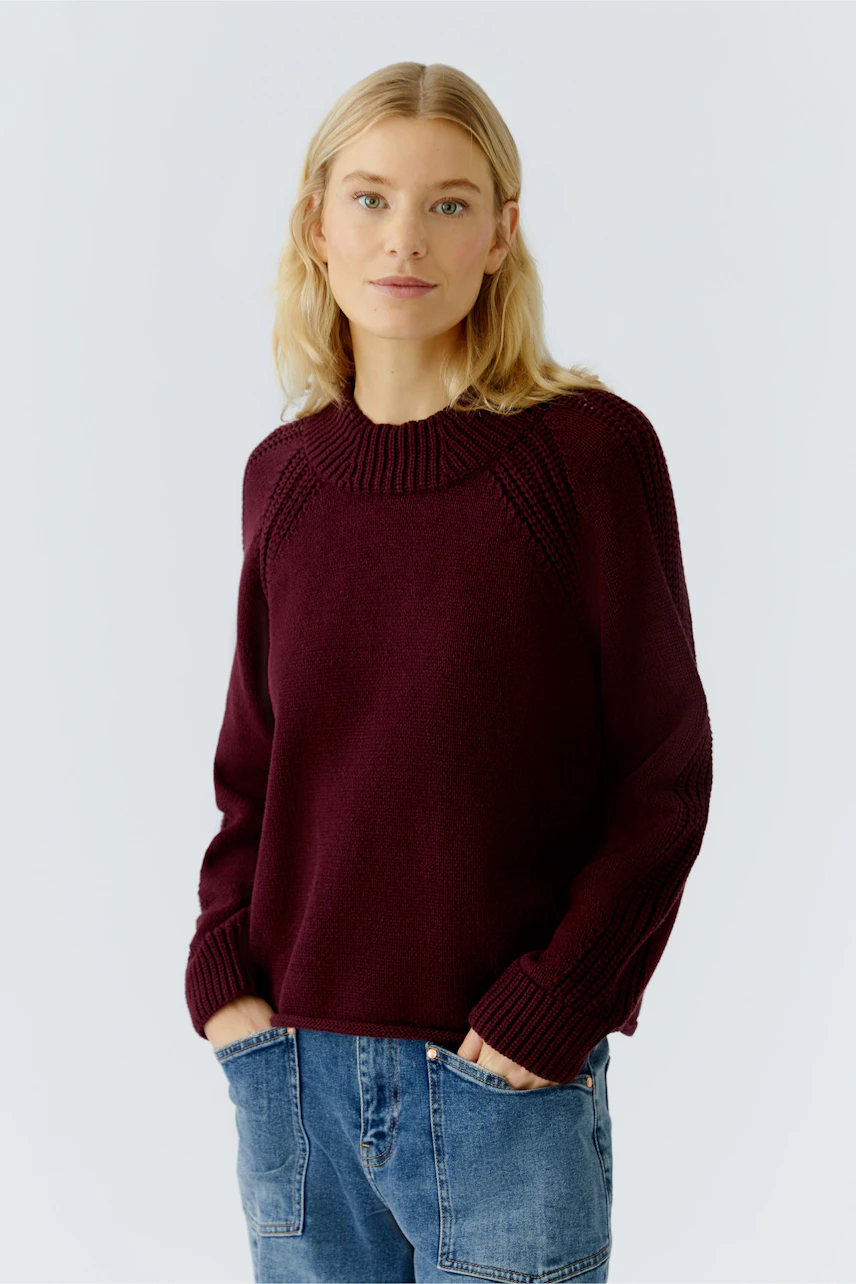 Damen-Pullover: Junge Frau in bordeauxfarbenem Strickpullover mit lässigem Schnitt und Rundhalsausschnitt.
