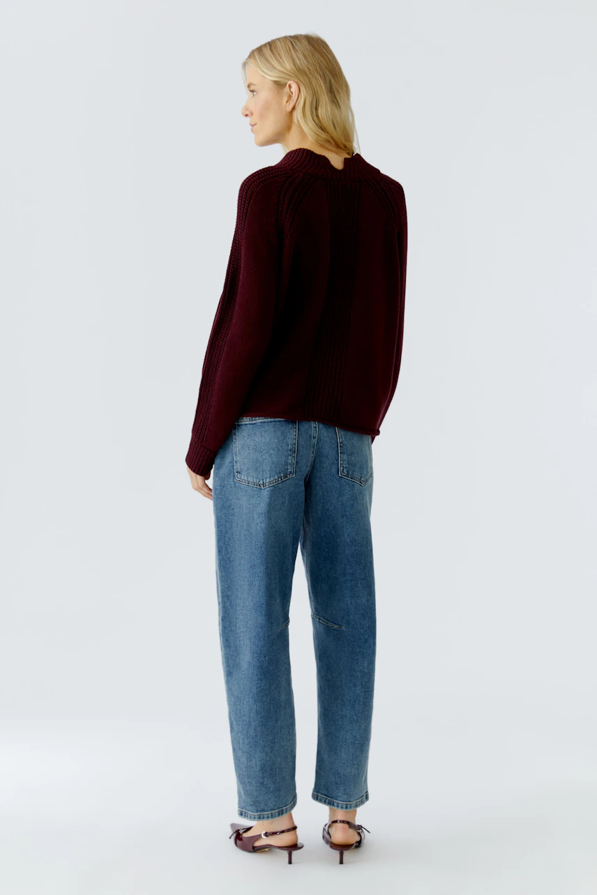 Damen-Pullover in Bordeaux: Frau mit lässigem Look, trägt den Pullover zu Jeans und Sandalen.