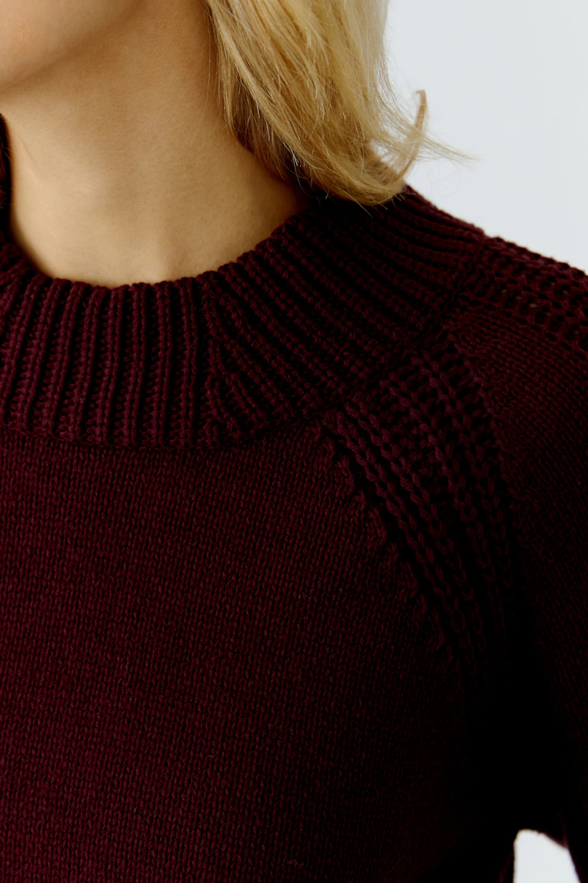 Damen-Pullover: Detailaufnahme eines burgunderfarbenen Strickpullovers mit hohem Kragen.