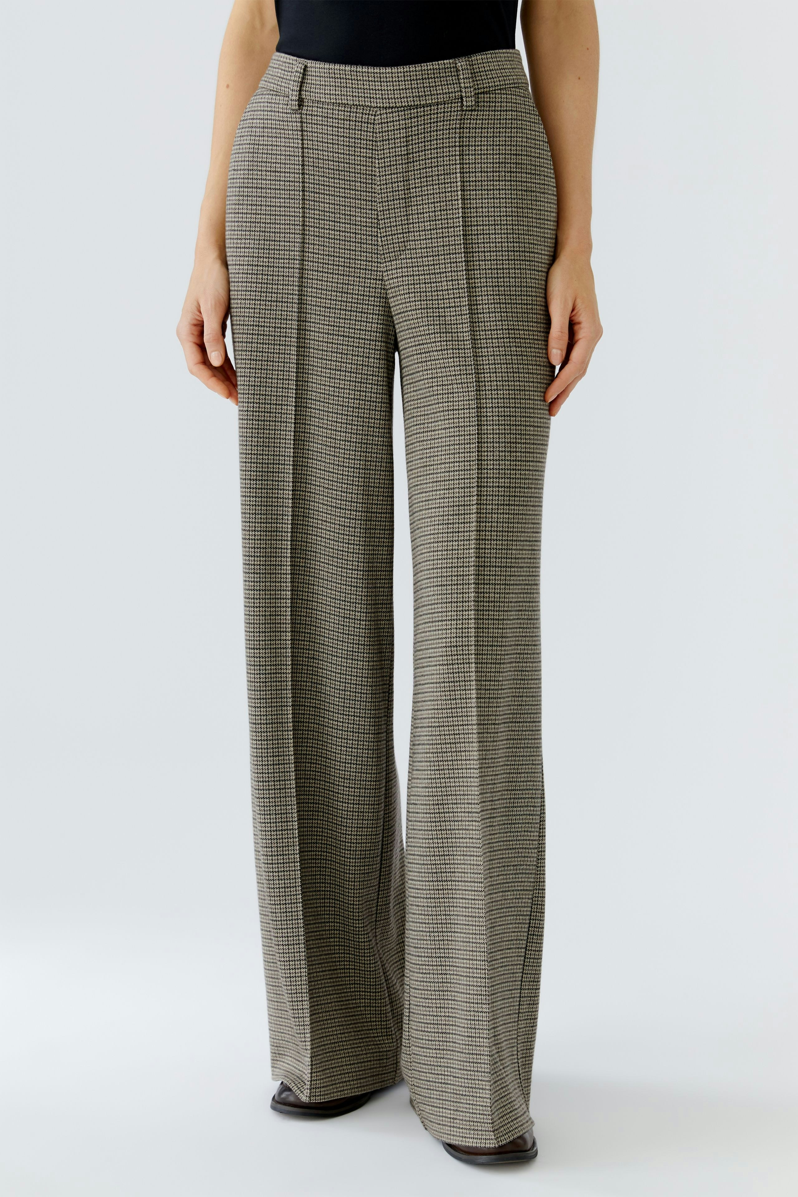 Stylish women's trousers: A woman in checkered wide-leg pants stands confidently.