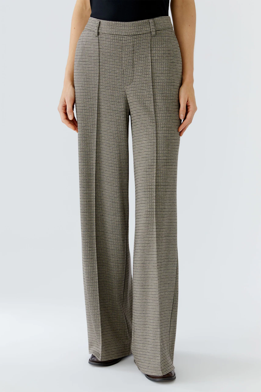 Stylish women's trousers: A woman in checkered wide-leg pants stands confidently.