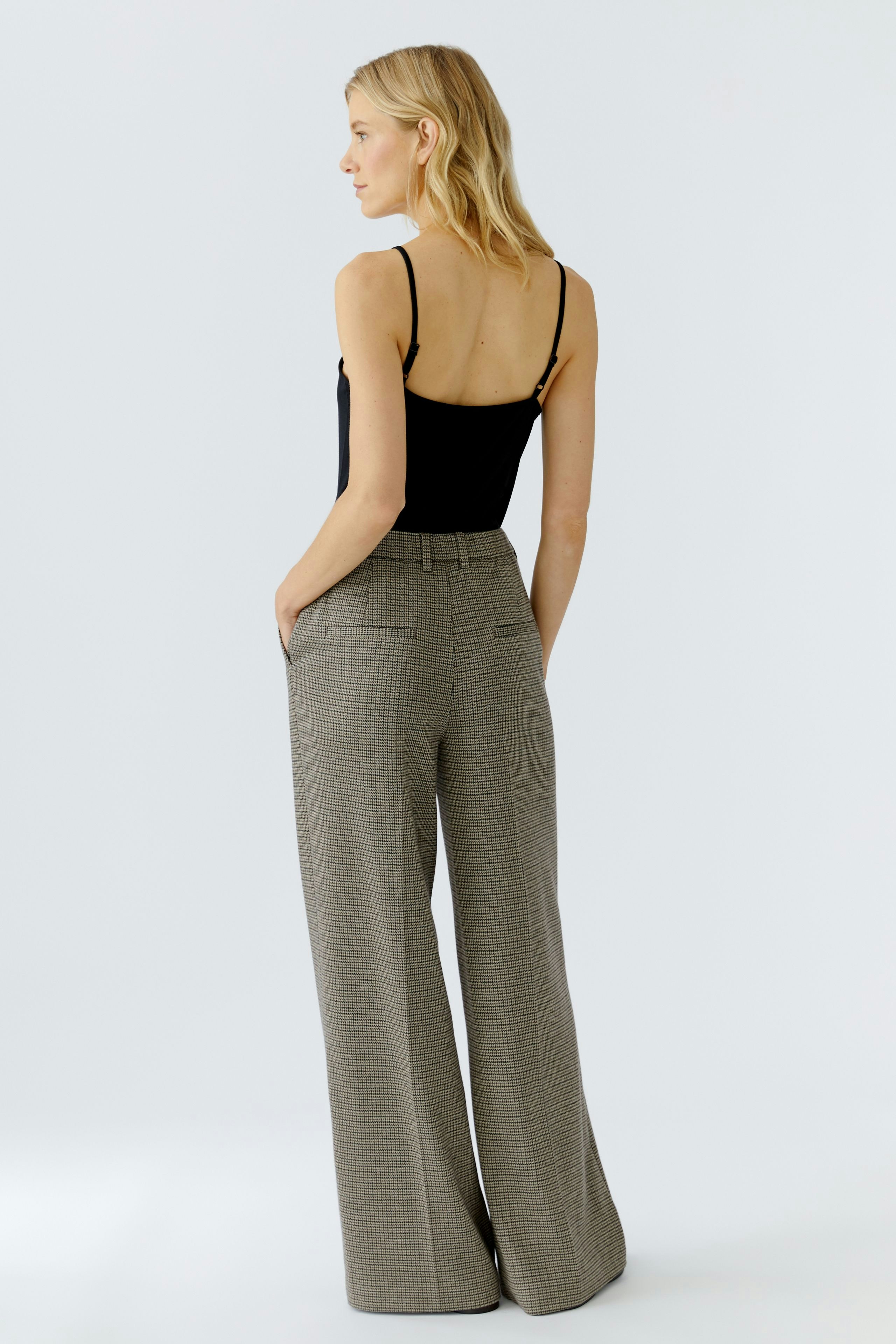 Casual women's trousers: A woman in wide-leg, checkered pants with a relaxed fit.