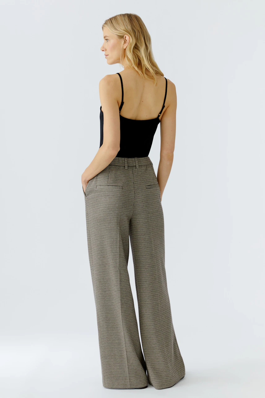 Casual women's trousers: A woman in wide-leg, checkered pants with a relaxed fit.