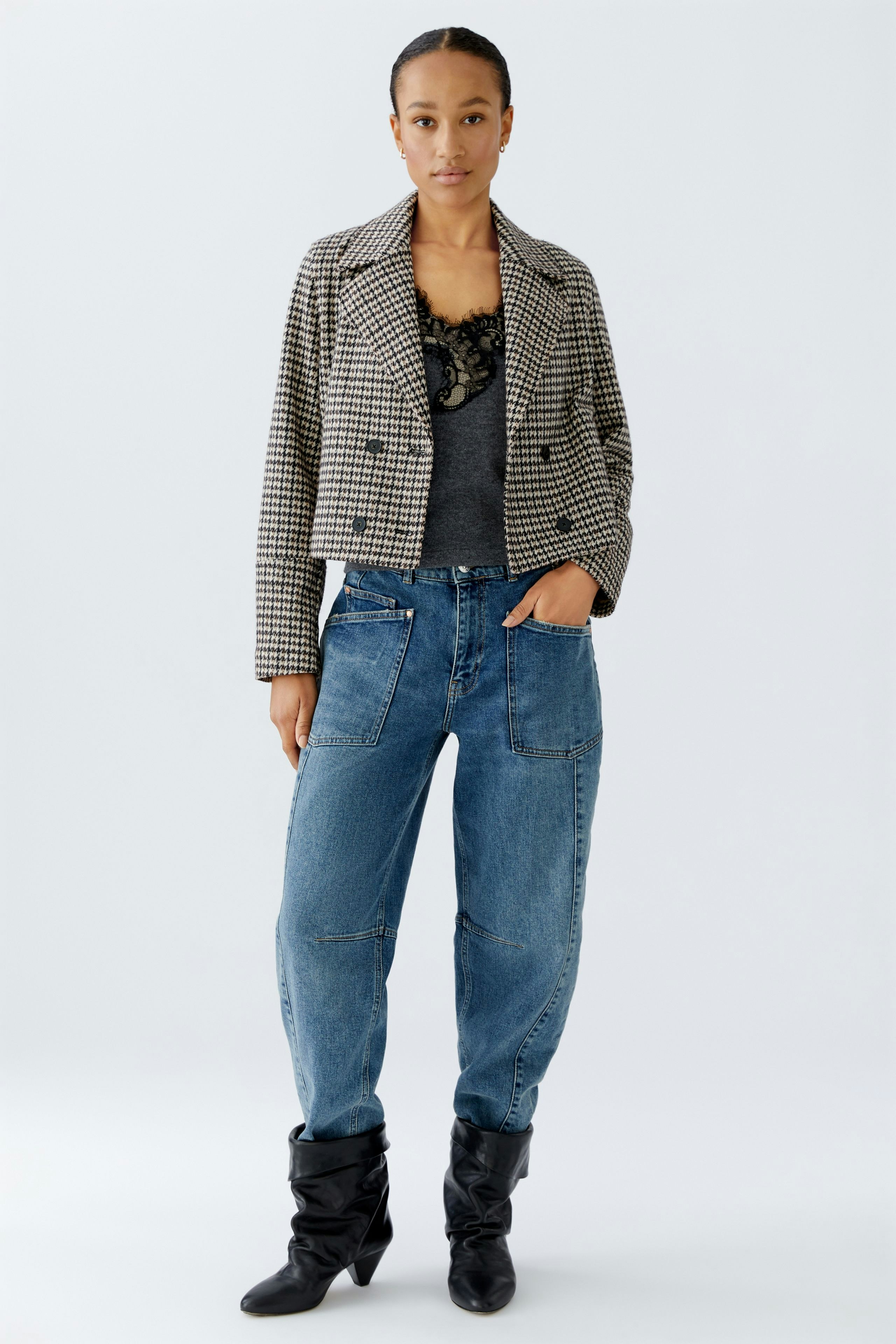 Stylish women's jacket: A woman in a checkered jacket over a gray top and relaxed jeans.