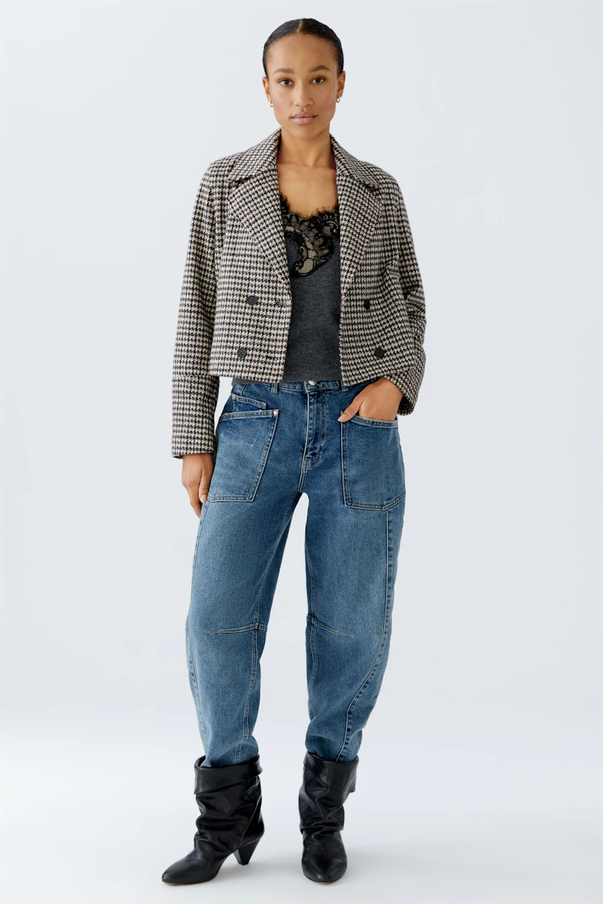 Stylish women's jacket: A woman in a checkered jacket over a gray top and relaxed jeans.