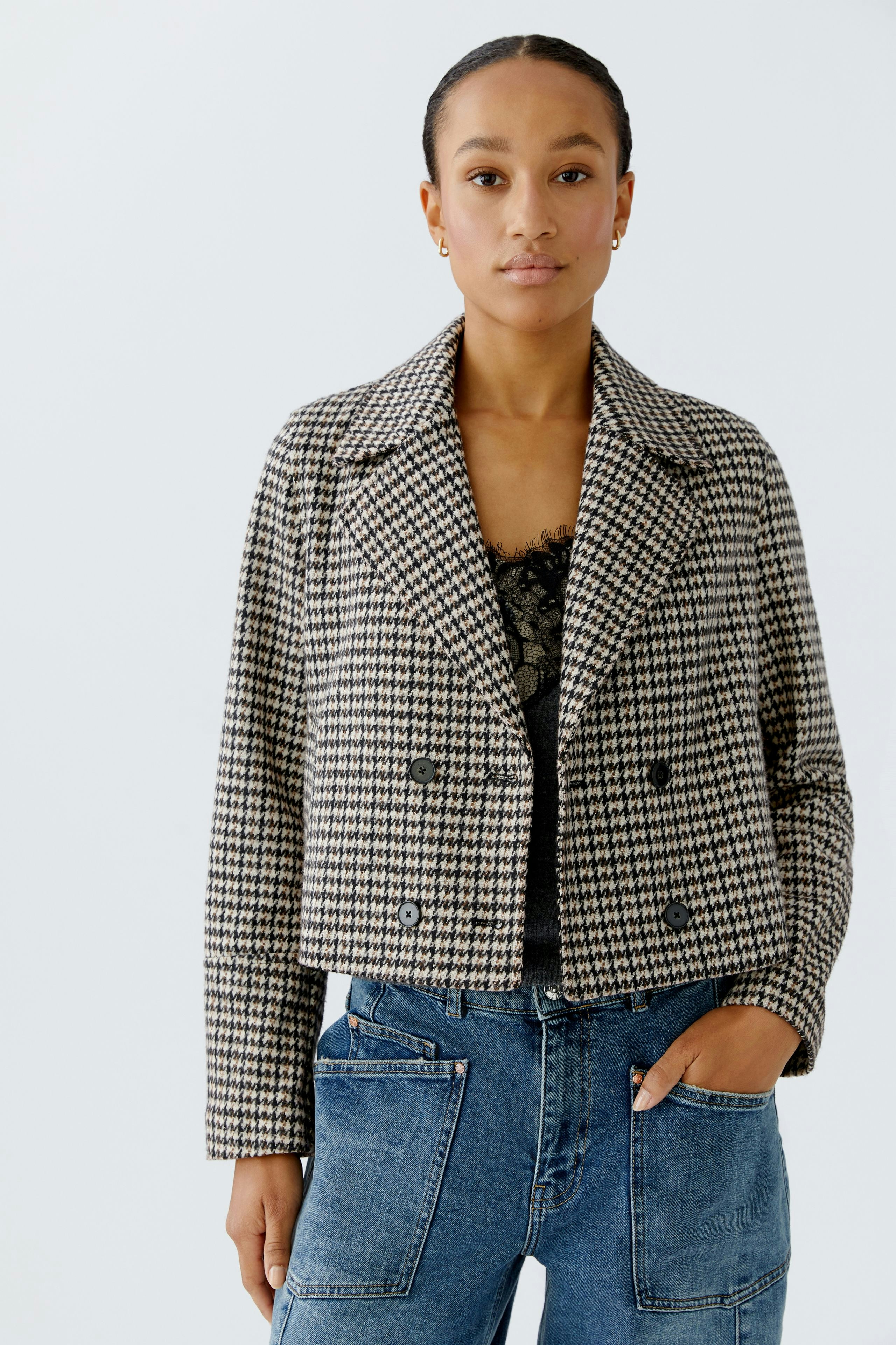 Stylish women's jacket: A woman in a checkered cropped jacket paired with casual jeans.