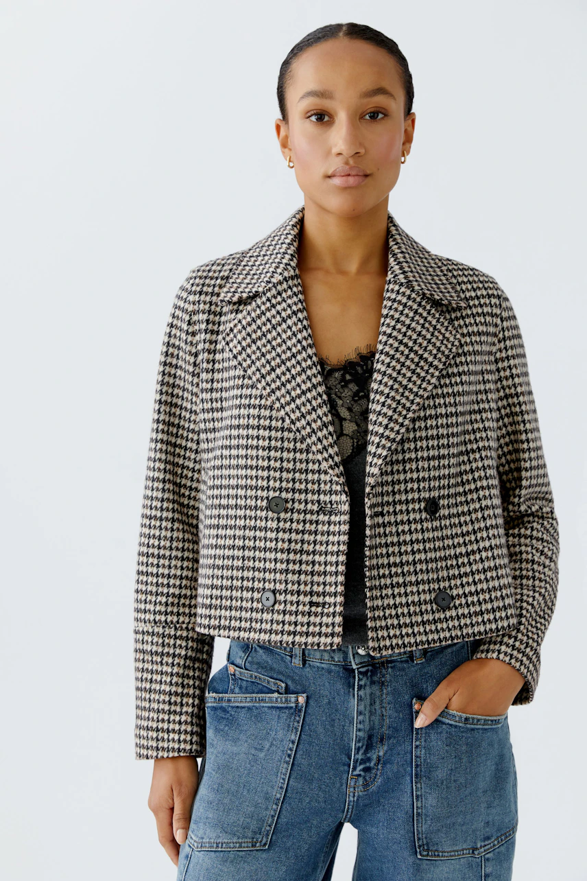 Stylish women's jacket: A woman in a checkered cropped jacket paired with casual jeans.