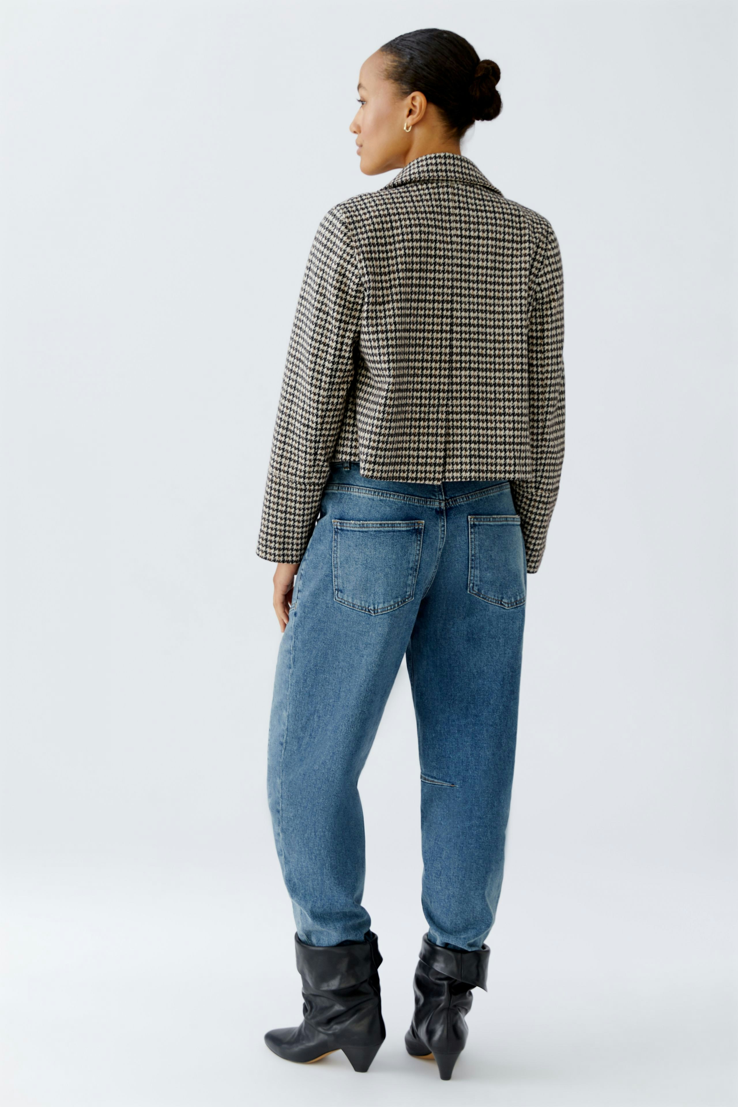 Stylish women's jacket: A woman in a cropped checkered jacket paired with relaxed jeans.
