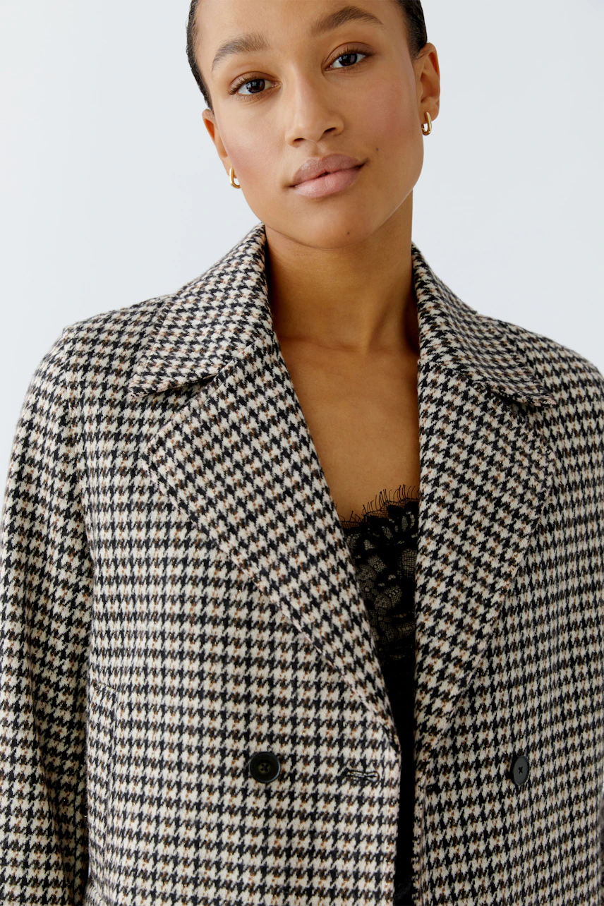 Stylish women's jacket: A woman in a houndstooth patterned jacket with a classic collar.