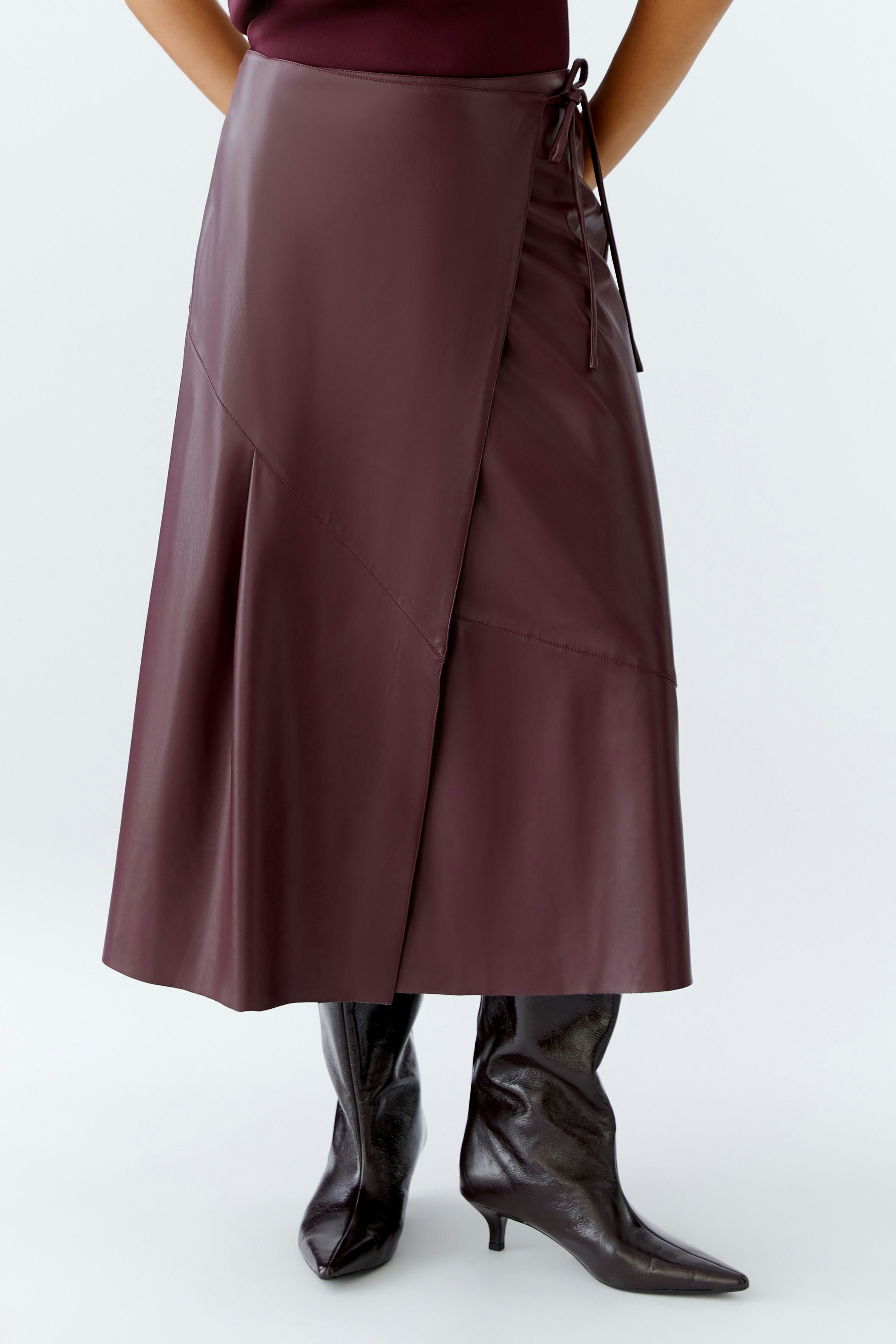 Stylish wrap skirt: Woman in a burgundy wrap skirt paired with knee-high boots.