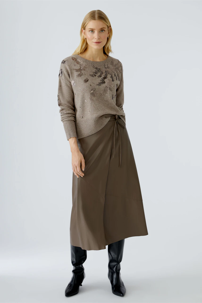 Modern wrap skirt: Woman in a stylish wrap skirt paired with a casual pullover.