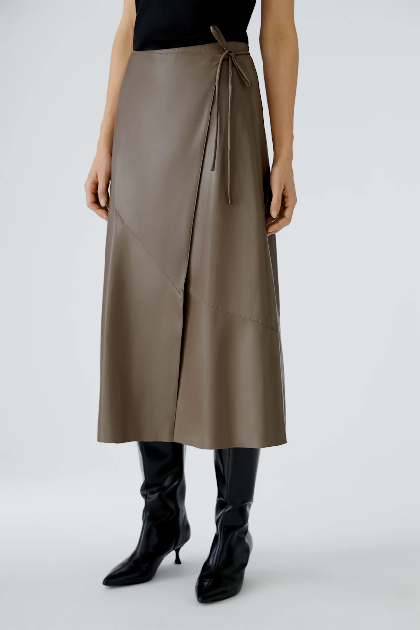 Stylish women's wrap skirt in brown faux leather, paired with sleek black boots.