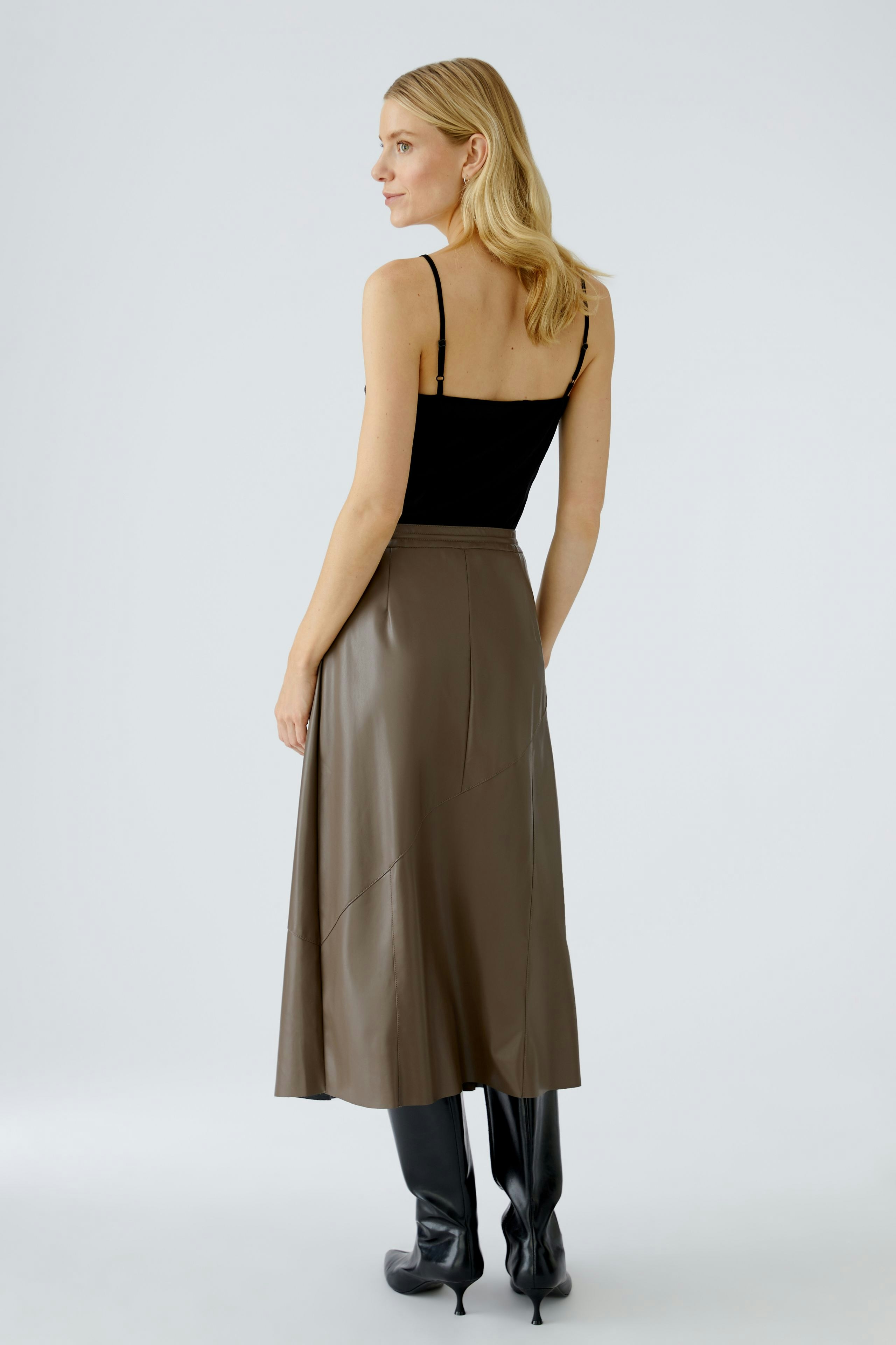 Modern wrap skirt: Woman in a brown wrap skirt paired with a black top and stylish boots.