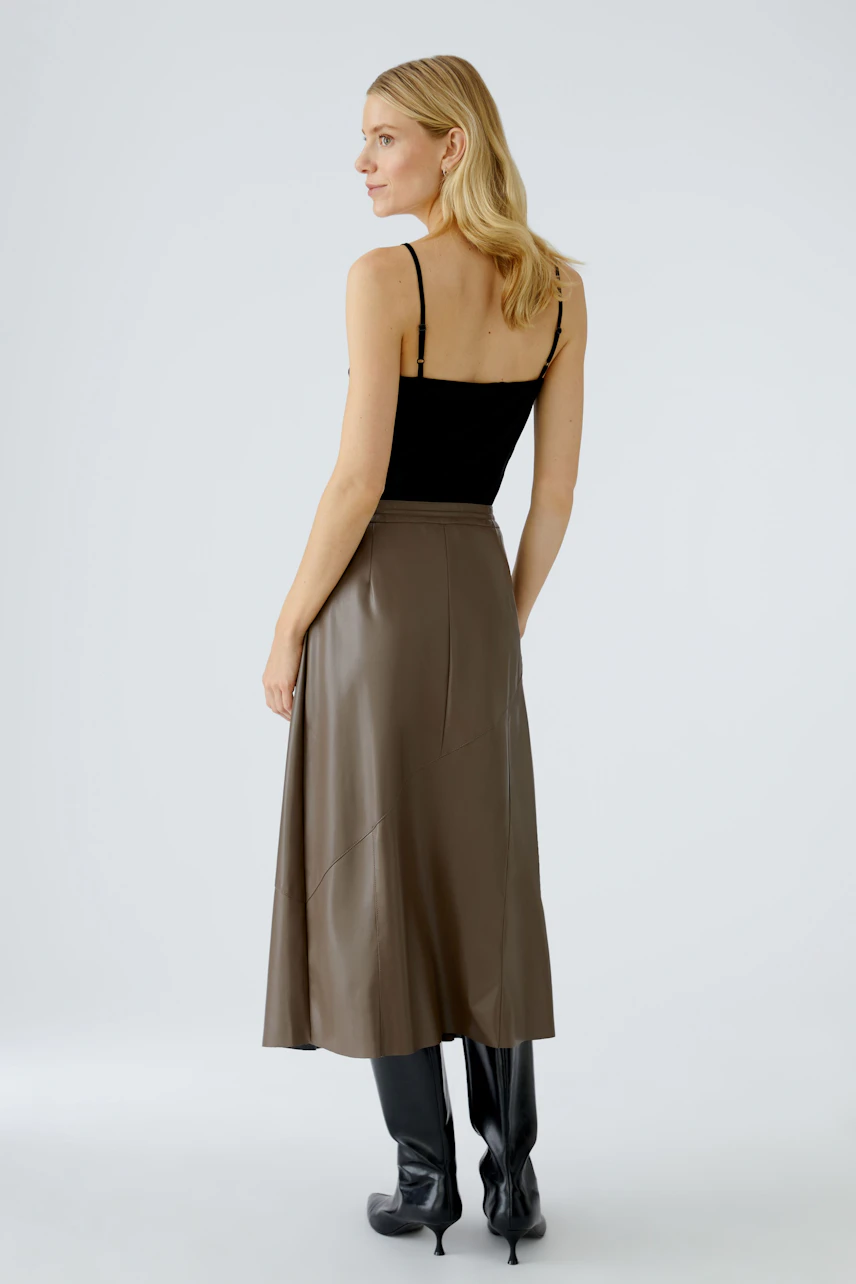 Modern wrap skirt: Woman in a brown wrap skirt paired with a black top and stylish boots.