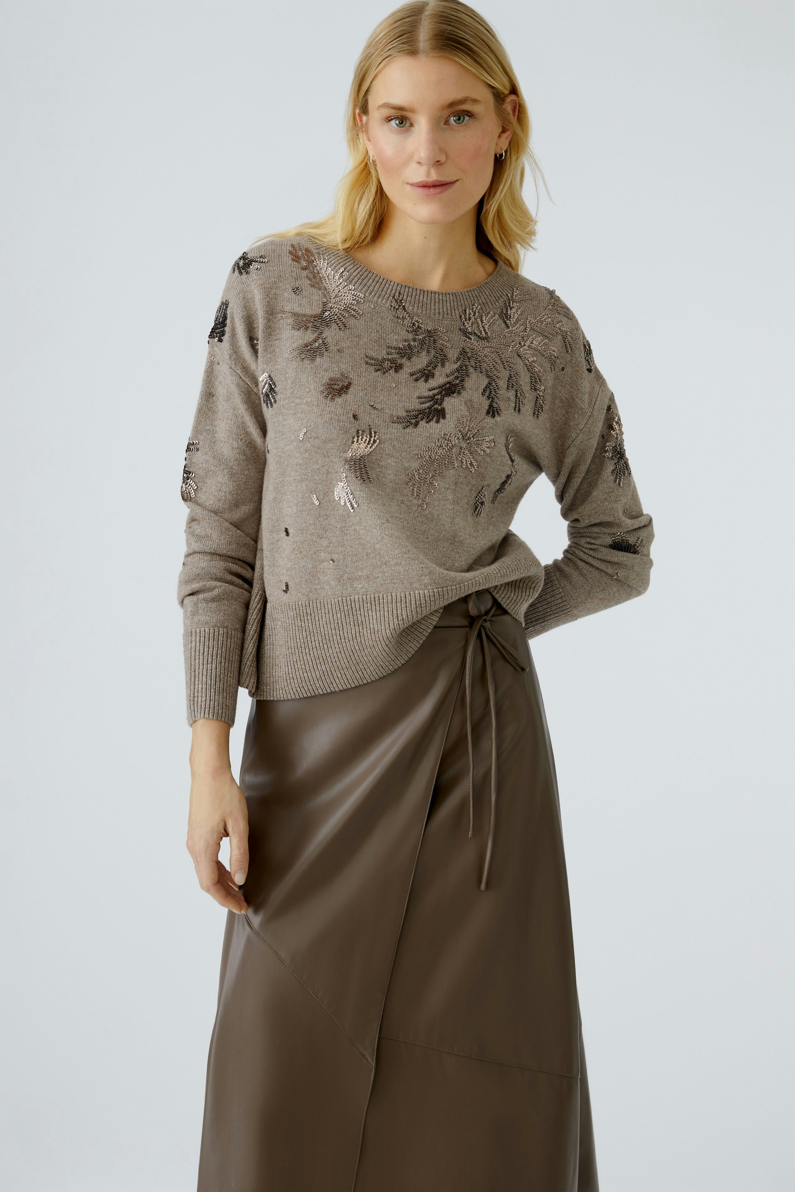 Casual wrap skirt: Woman in a brown wrap skirt paired with a stylish pullover, showcasing a relaxed look.