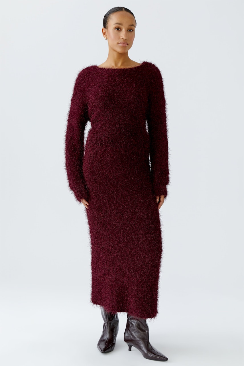 Cozy women's knit skirt: A woman in a burgundy knit skirt with long sleeves stands confidently.