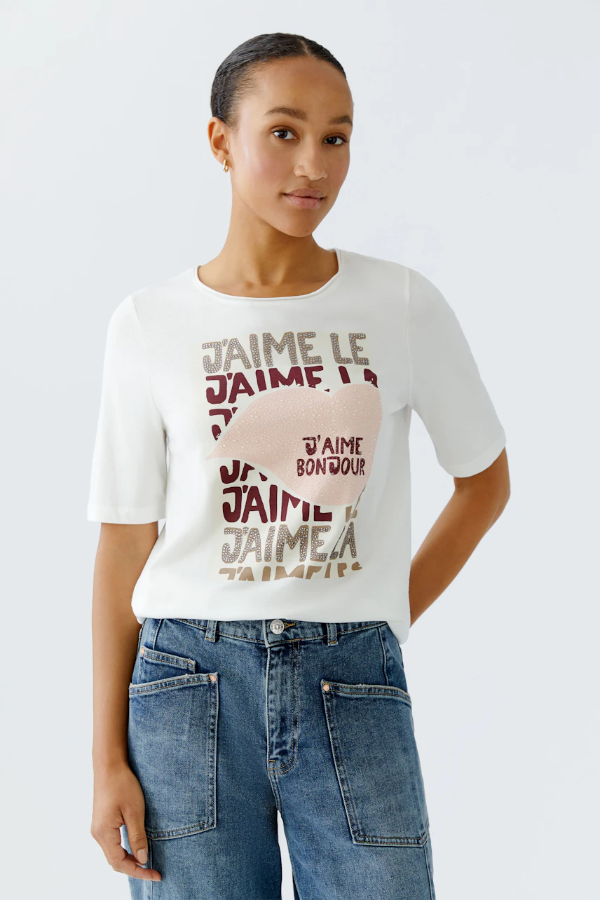 Casual women's T-shirt: Young woman in a white tee with colorful text and relaxed fit jeans.