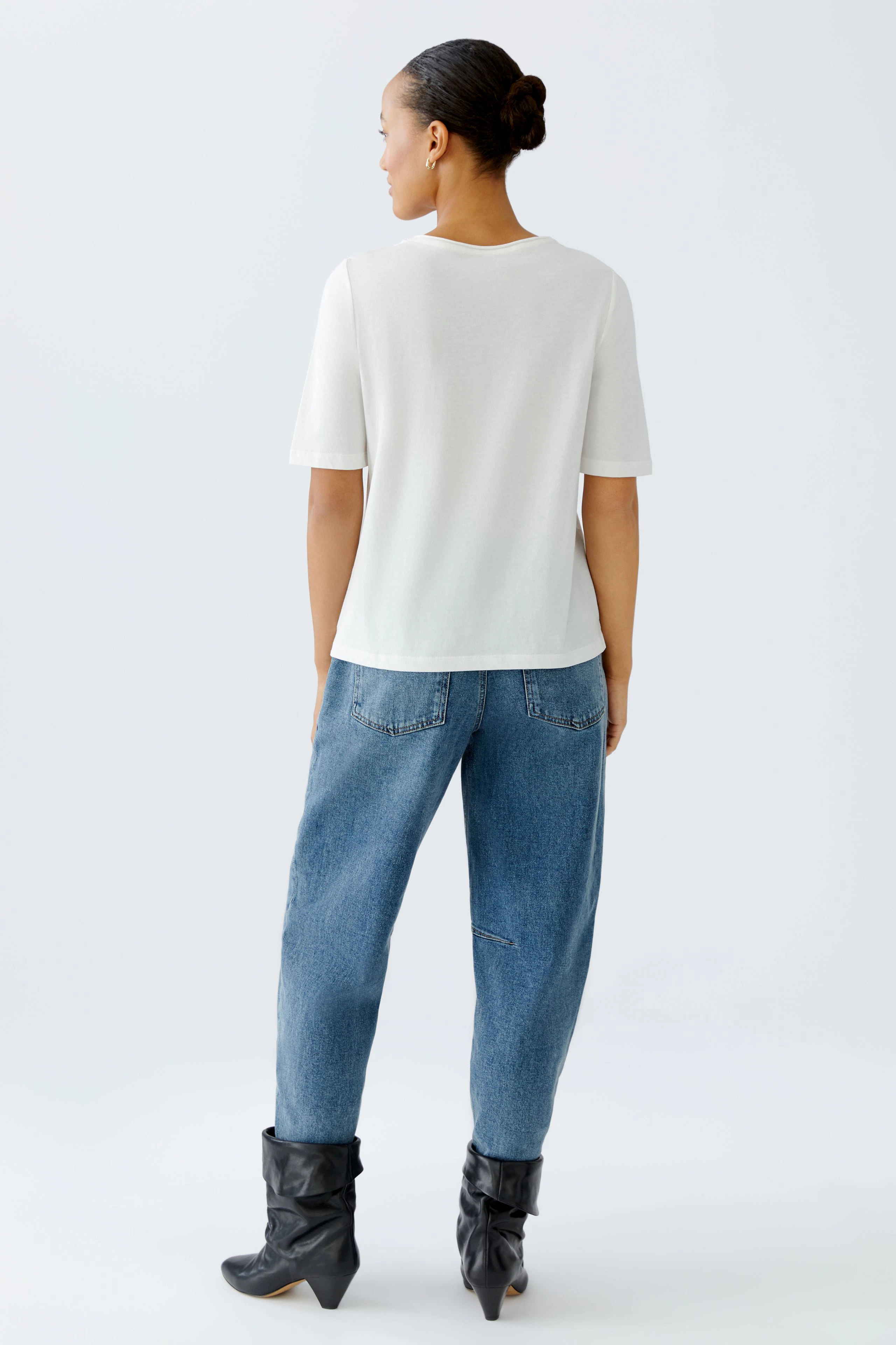 Damen-T-Shirt: Frau in weißem T-Shirt und lässigen Jeans, von hinten zu sehen.
