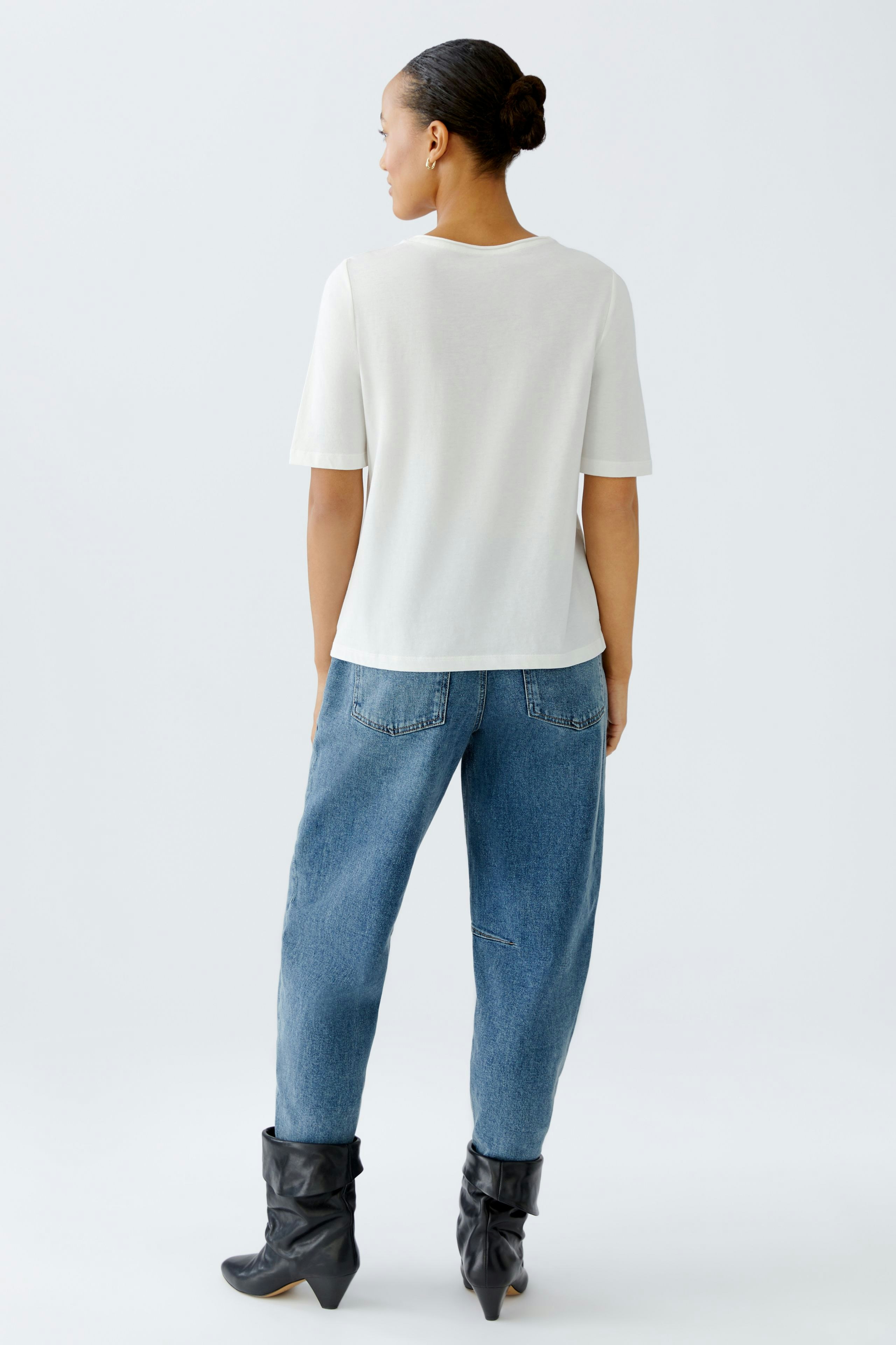Casual women's T-shirt: A woman in a white short-sleeve T-shirt and relaxed jeans, showcasing a laid-back style.