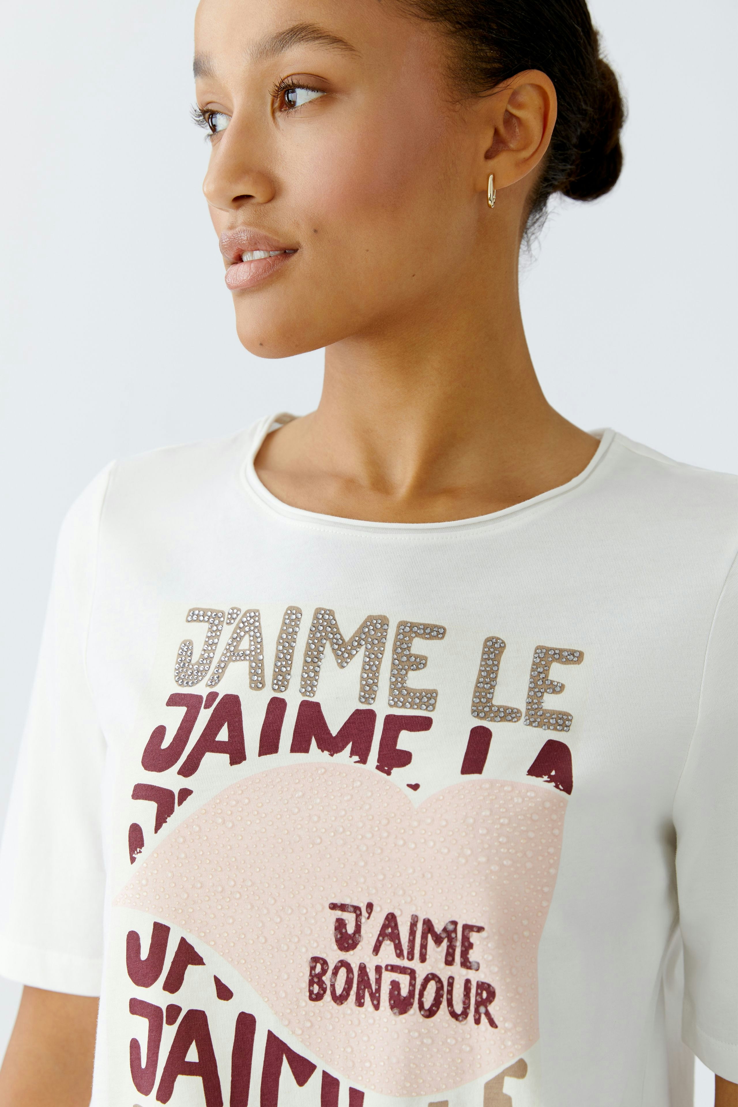 Casual women's T-shirt: Young woman in a white tee with colorful text and a playful design.