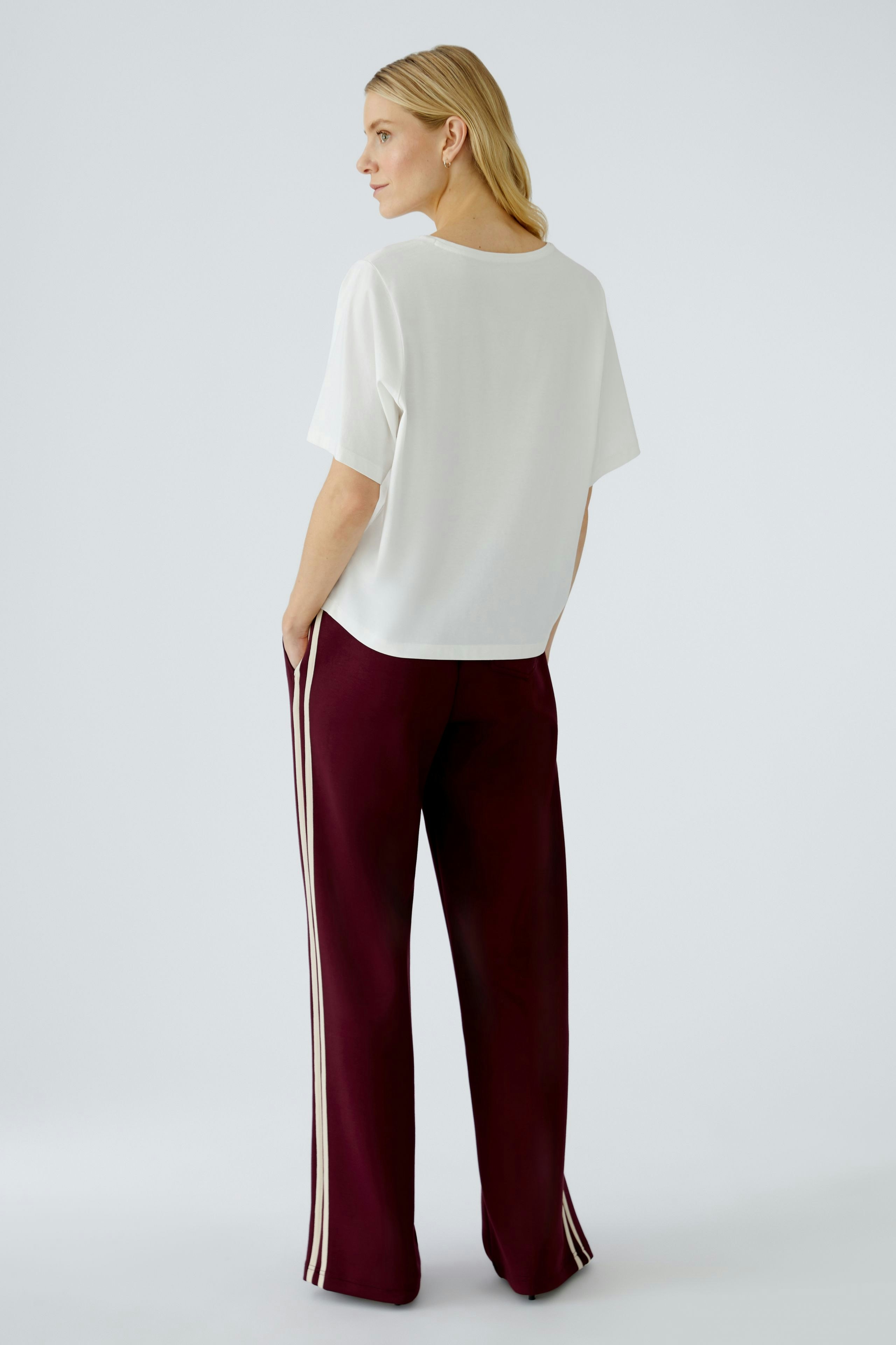 Damen-T-Shirt: Frau in weißem, lässigem T-Shirt mit lockerer Passform und sportlicher Hose.