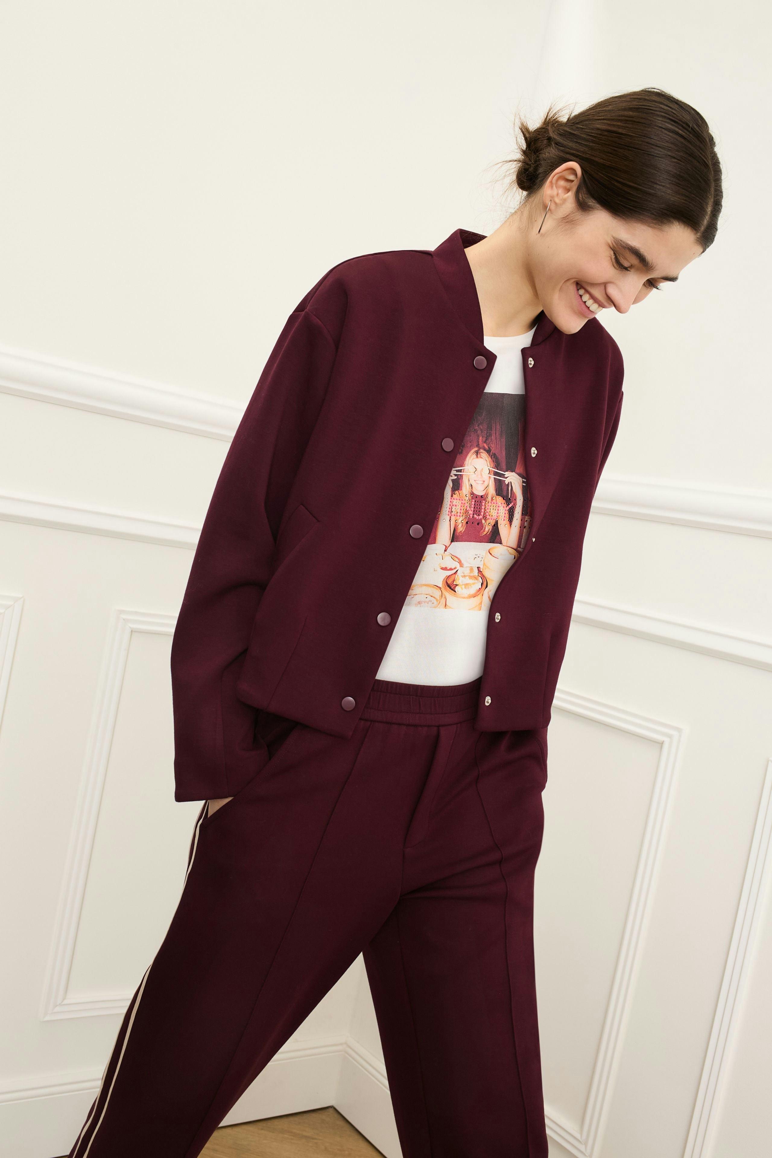 Damen-T-Shirt: Frau in lässigem T-Shirt mit Print und bequemer Jacke, kombiniert mit sportlichen Hosen.