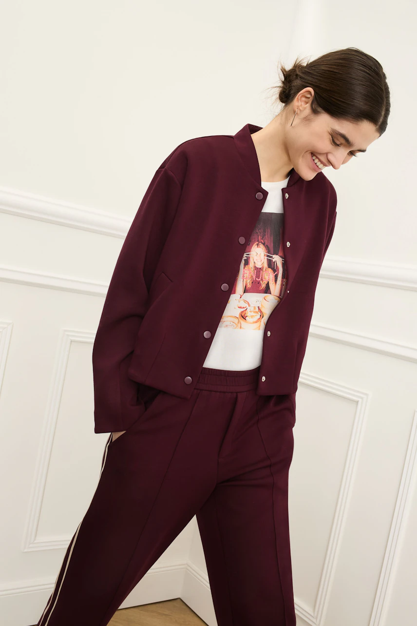 Damen-T-Shirt: Frau in lässigem T-Shirt mit Print und bequemer Jacke, kombiniert mit sportlichen Hosen.