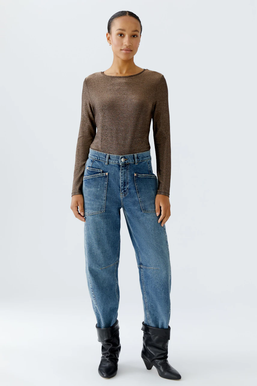 Casual long-sleeve shirt: Woman in a brown top paired with relaxed-fit jeans, showcasing a laid-back style.