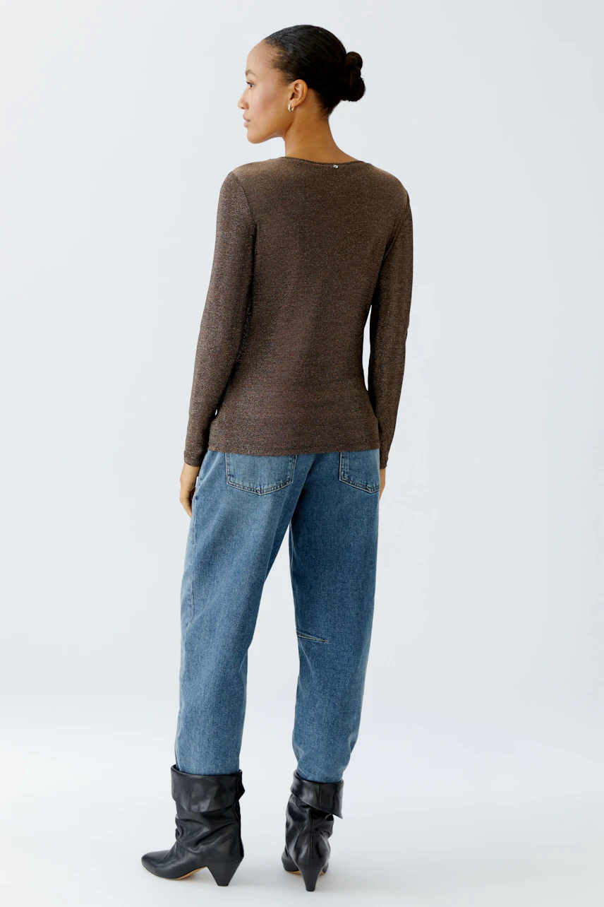 Casual long-sleeve shirt: Woman in a brown top paired with relaxed jeans, showcasing a comfortable style.