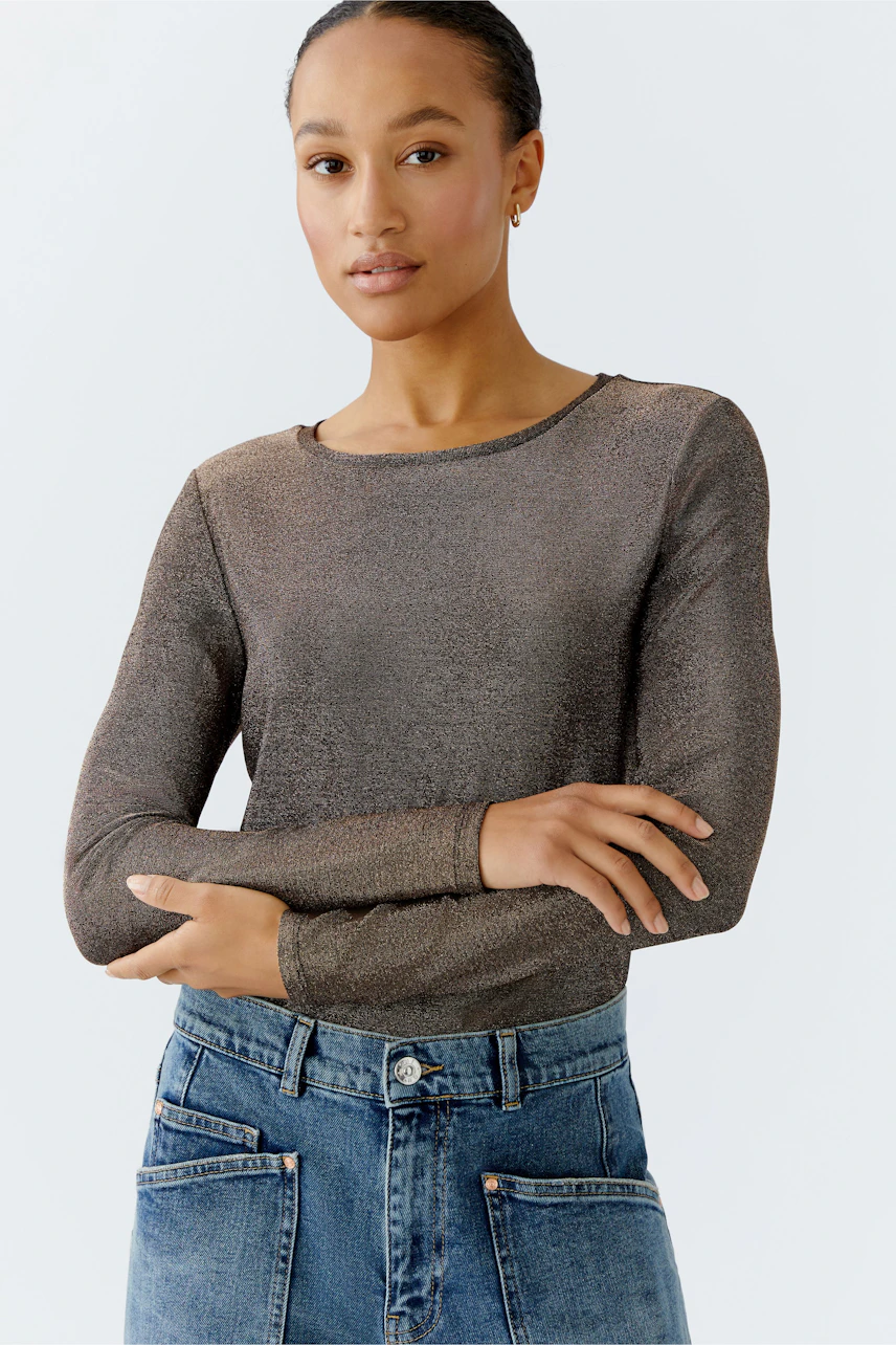 Casual long-sleeve shirt: Woman in a bronze top with a relaxed fit, paired with high-waisted jeans.