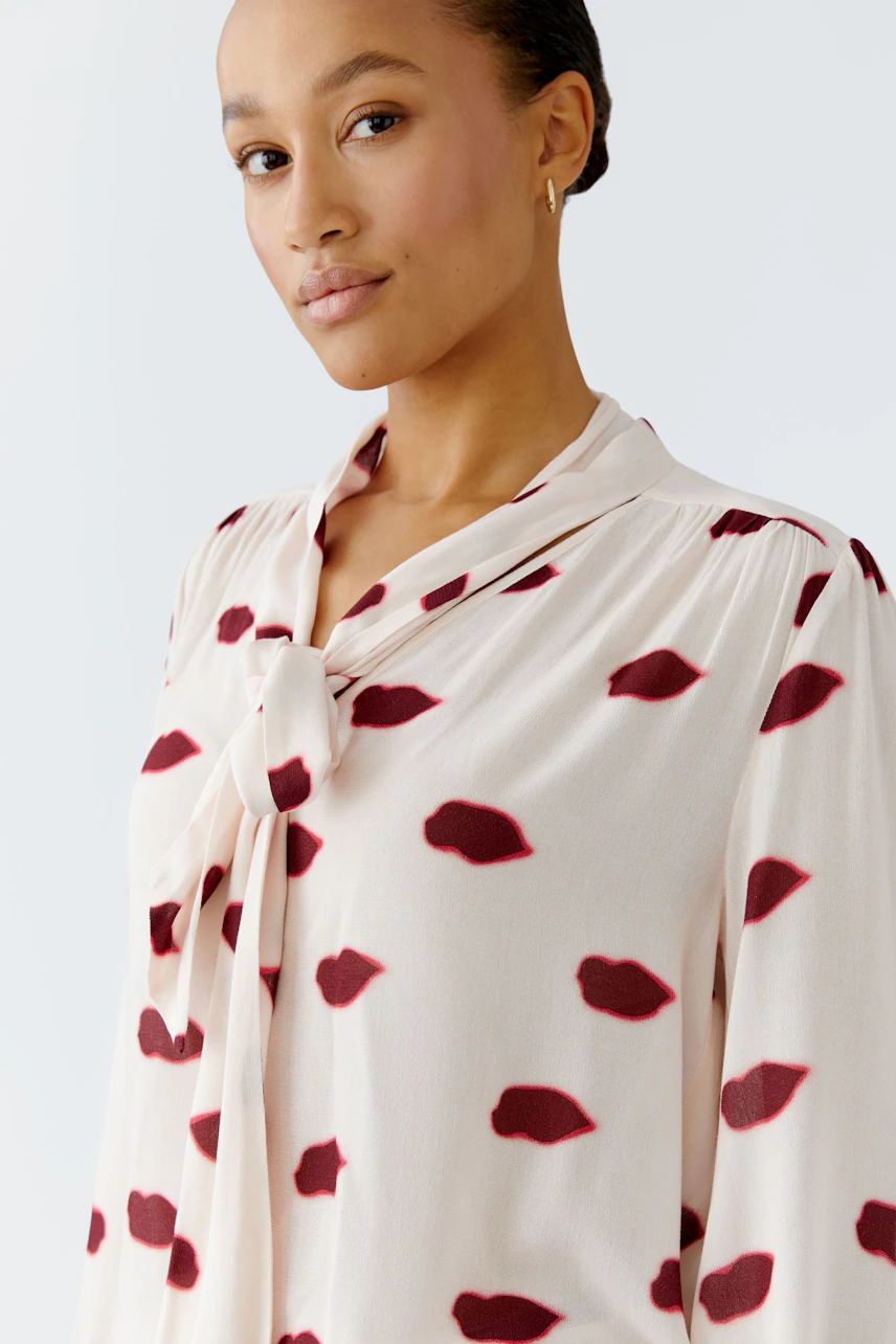Lightweight blouse with a tie detail, featuring a woman with a natural look and a playful print.