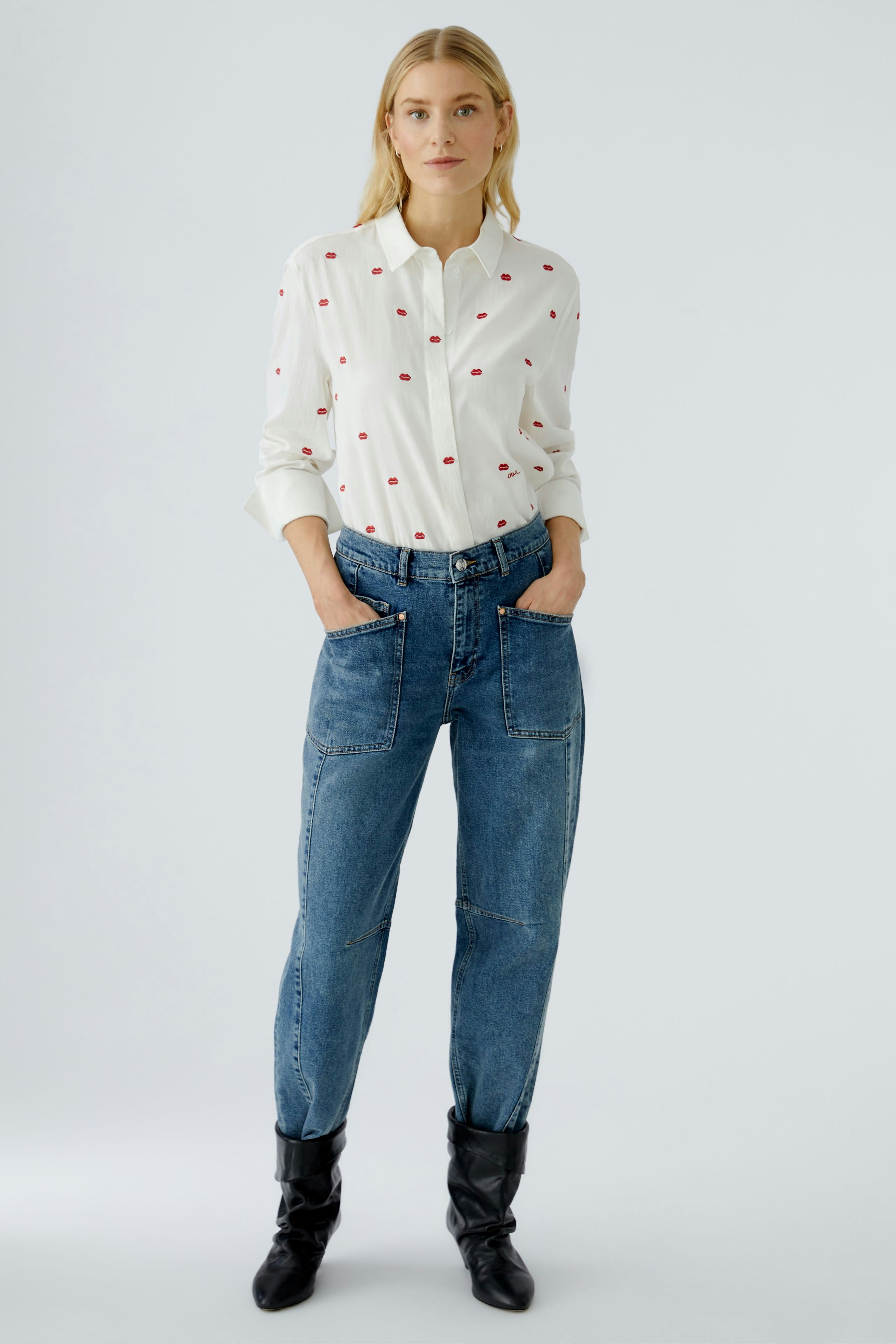 Casual women's blouse: A woman in a white blouse with red dots and relaxed-fit jeans.