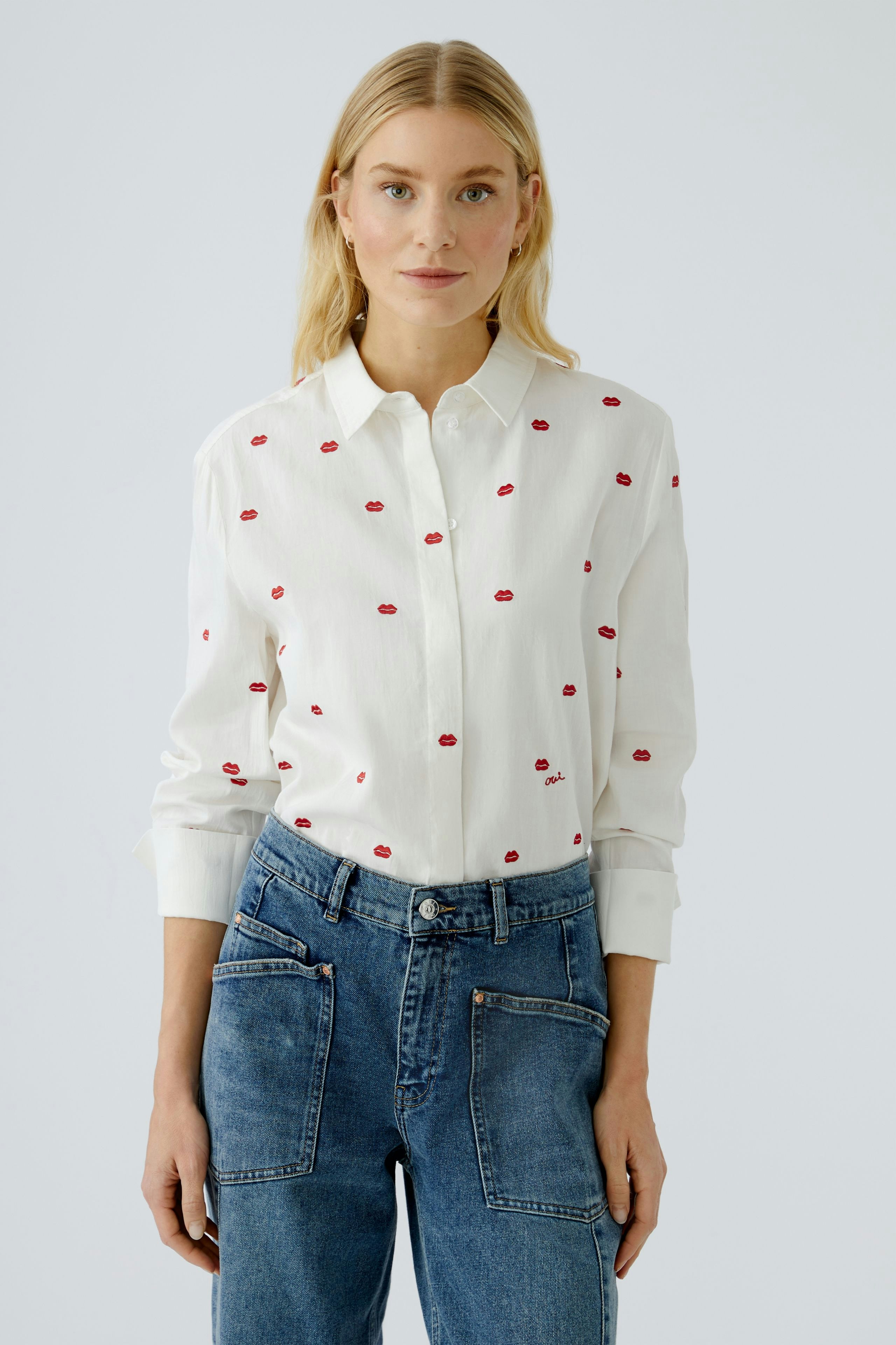 Casual women's blouse: Young woman in a white shirt with red lips design, paired with denim jeans.