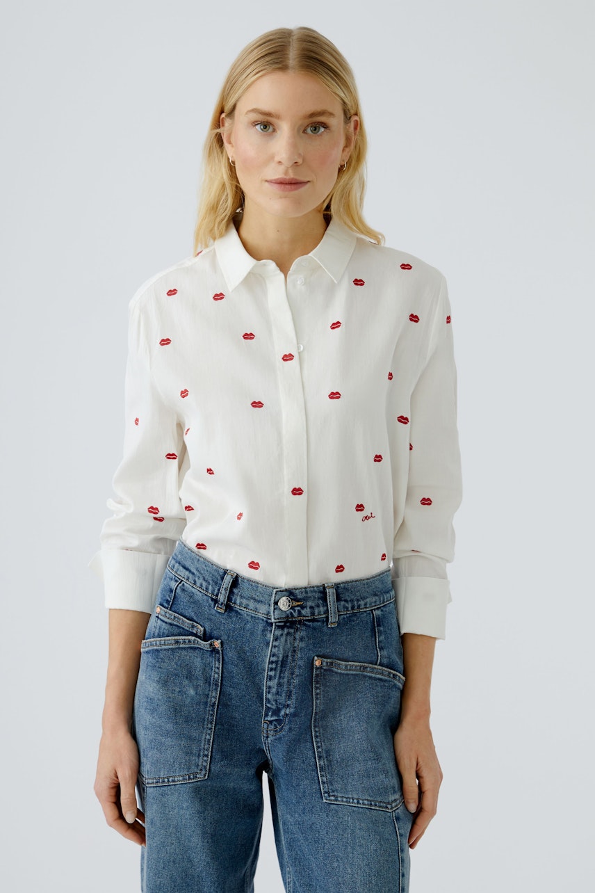 Damen-Bluse: Frau in weißer Bluse mit roten Lippenstickern und lässigen Jeans.