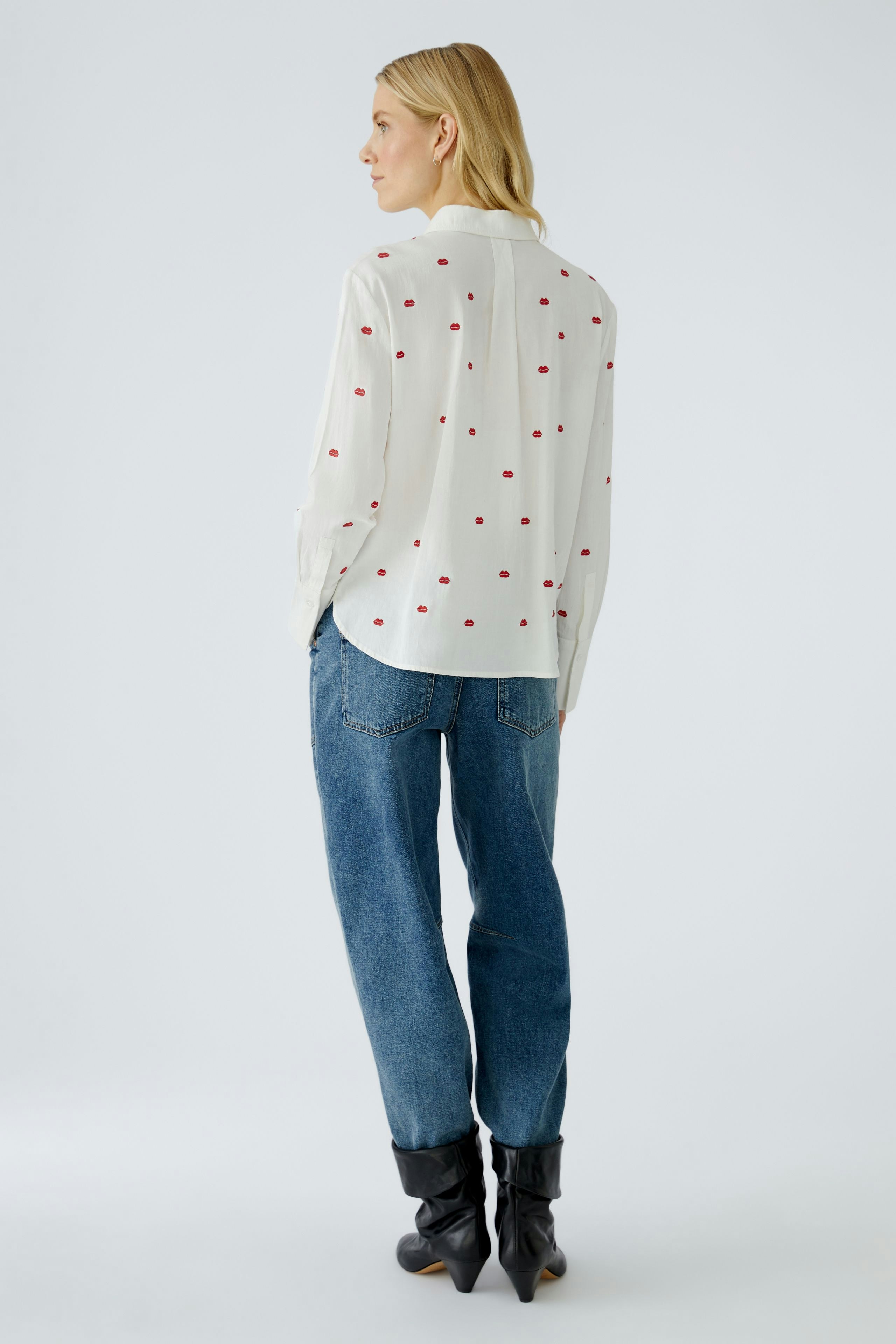 Casual women's blouse: A woman in a white blouse with red dots and relaxed-fit jeans.