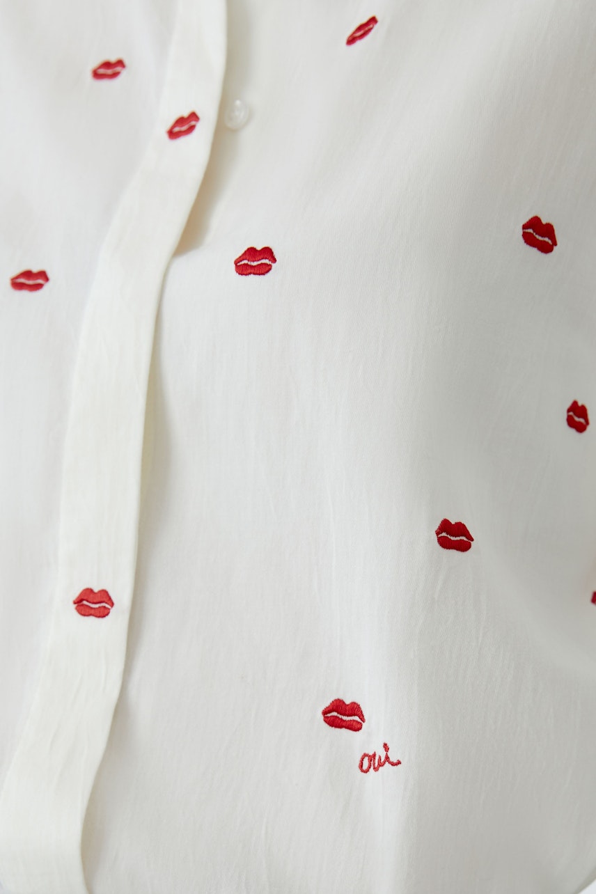 Lässige Damen-Bluse: Weiße Bluse mit roten Lippenstickern, ideal für einen entspannten Look.