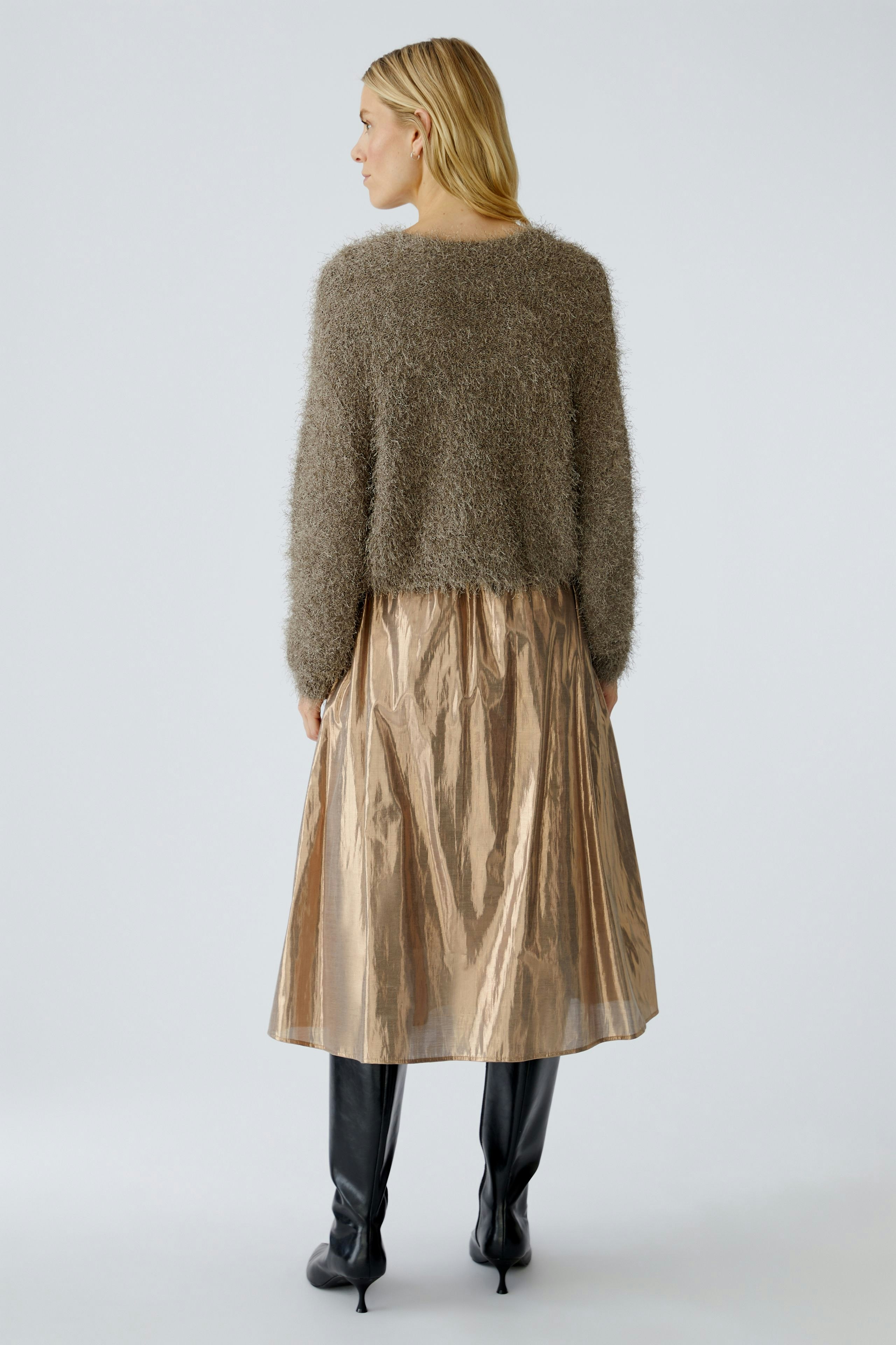 Cozy women's cardigan: A woman in a fluffy brown cardigan paired with a shiny skirt.
