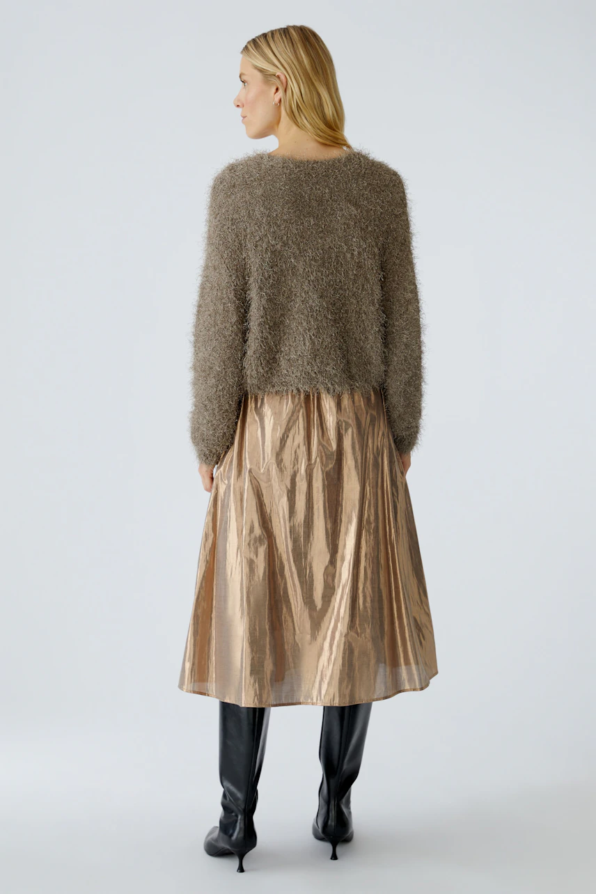 Damen-Strickjacke: Frau mit flauschiger, brauner Strickjacke und glänzendem Rock von hinten.