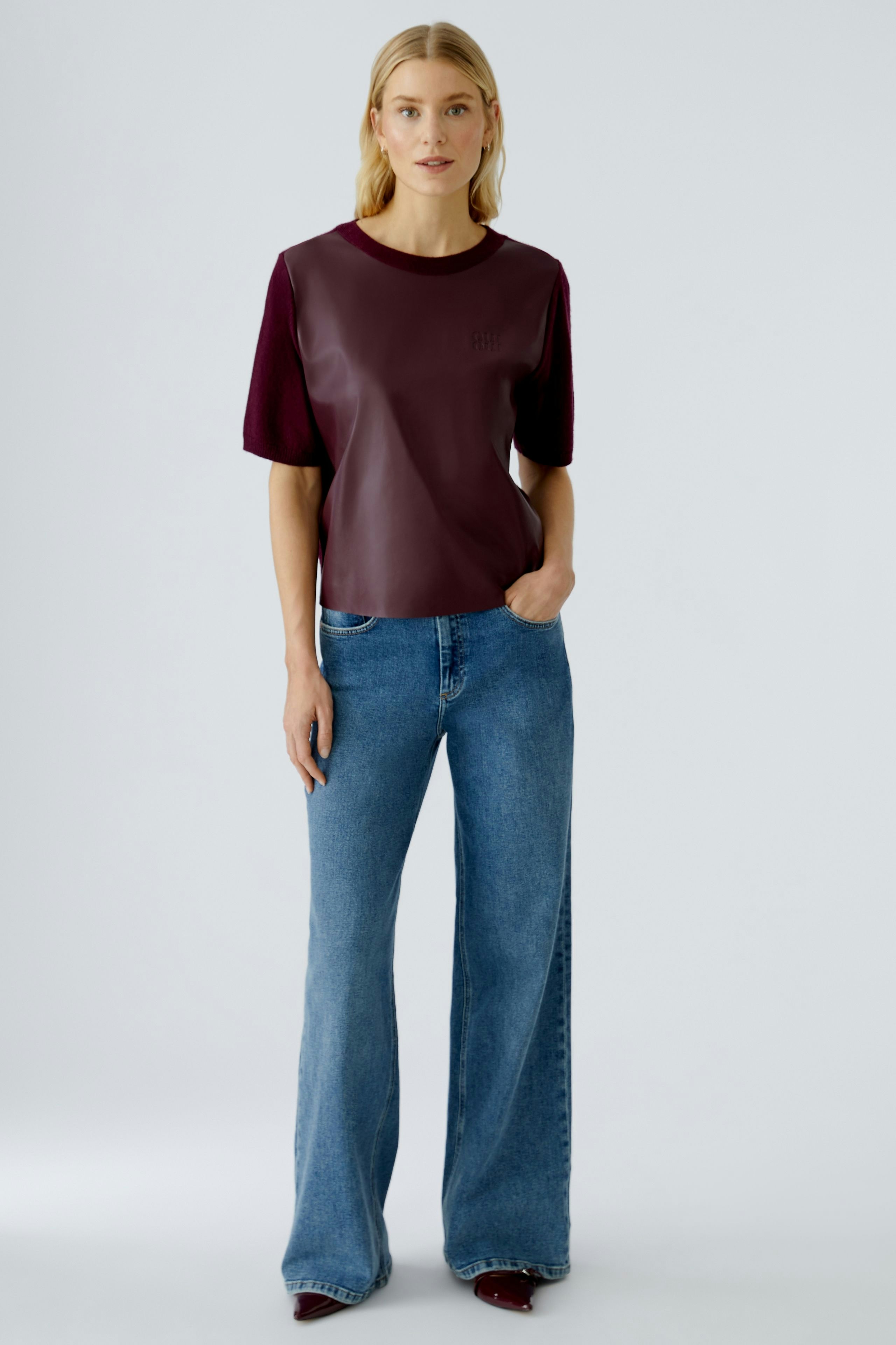 Damen-Pullover: Frau trägt einen lässigen, bordeauxfarbenen Pullover mit kurzen Ärmeln und Jeans.