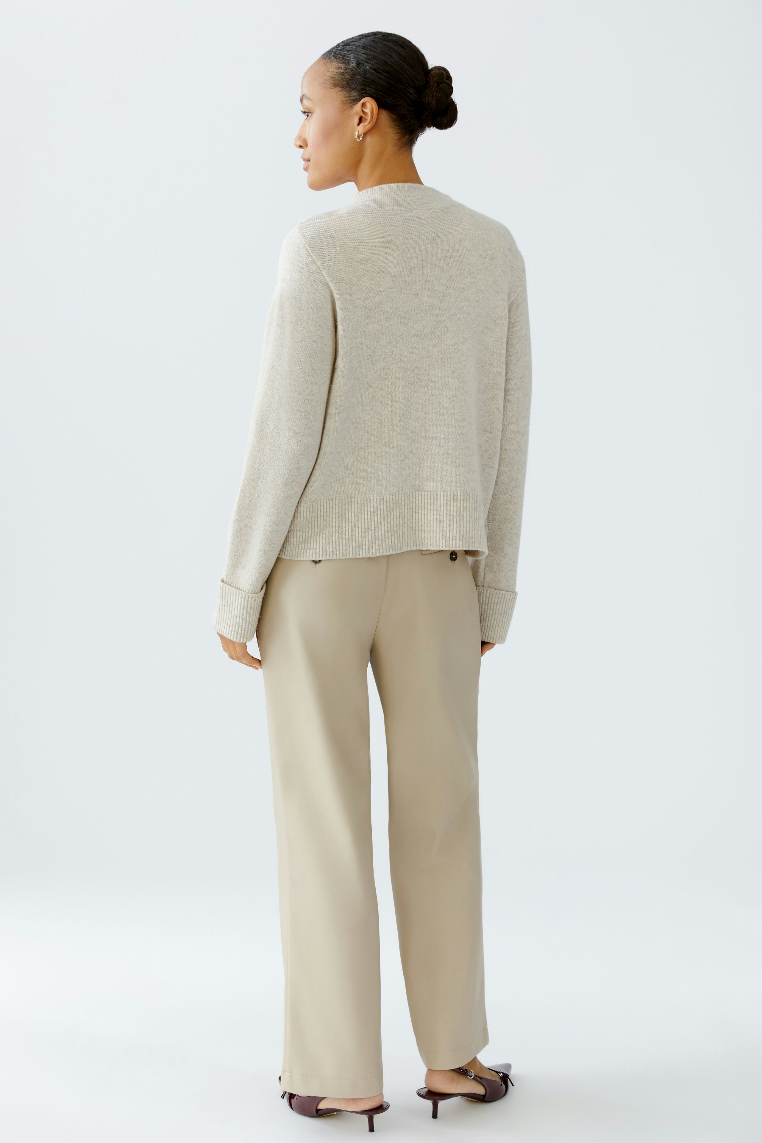 Casual women's pullover: A woman in a light beige pullover with a relaxed fit, paired with wide trousers.