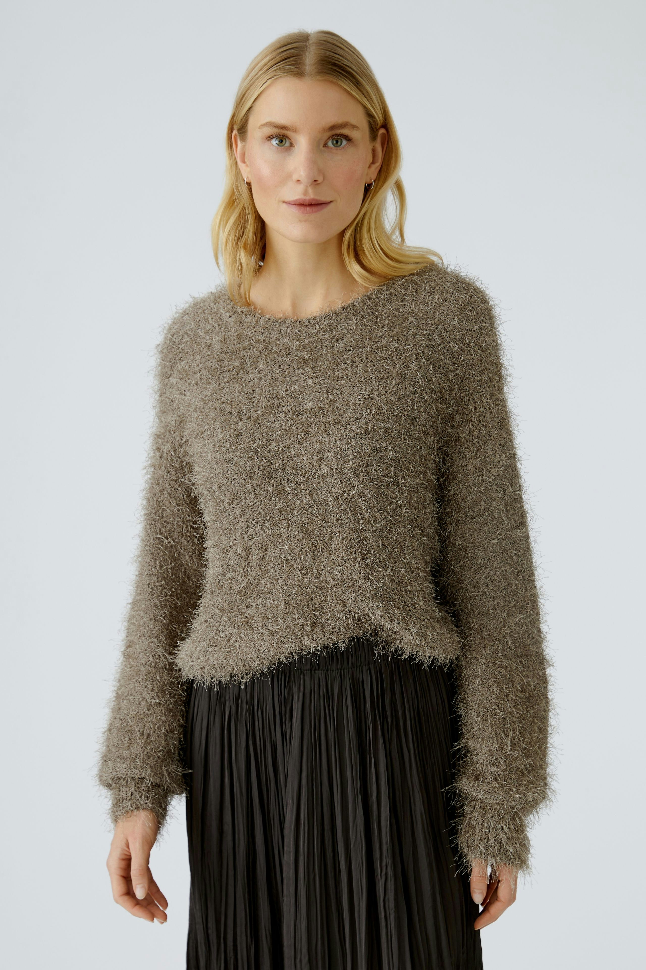 Casual women's pullover: Woman in a soft, fuzzy brown pullover paired with a pleated black skirt.