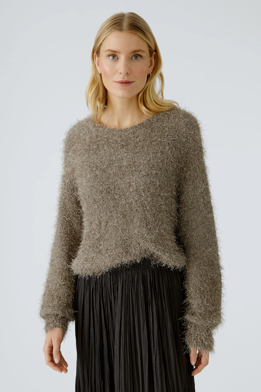 Casual women's pullover: Woman in a soft, fuzzy brown pullover paired with a pleated black skirt.