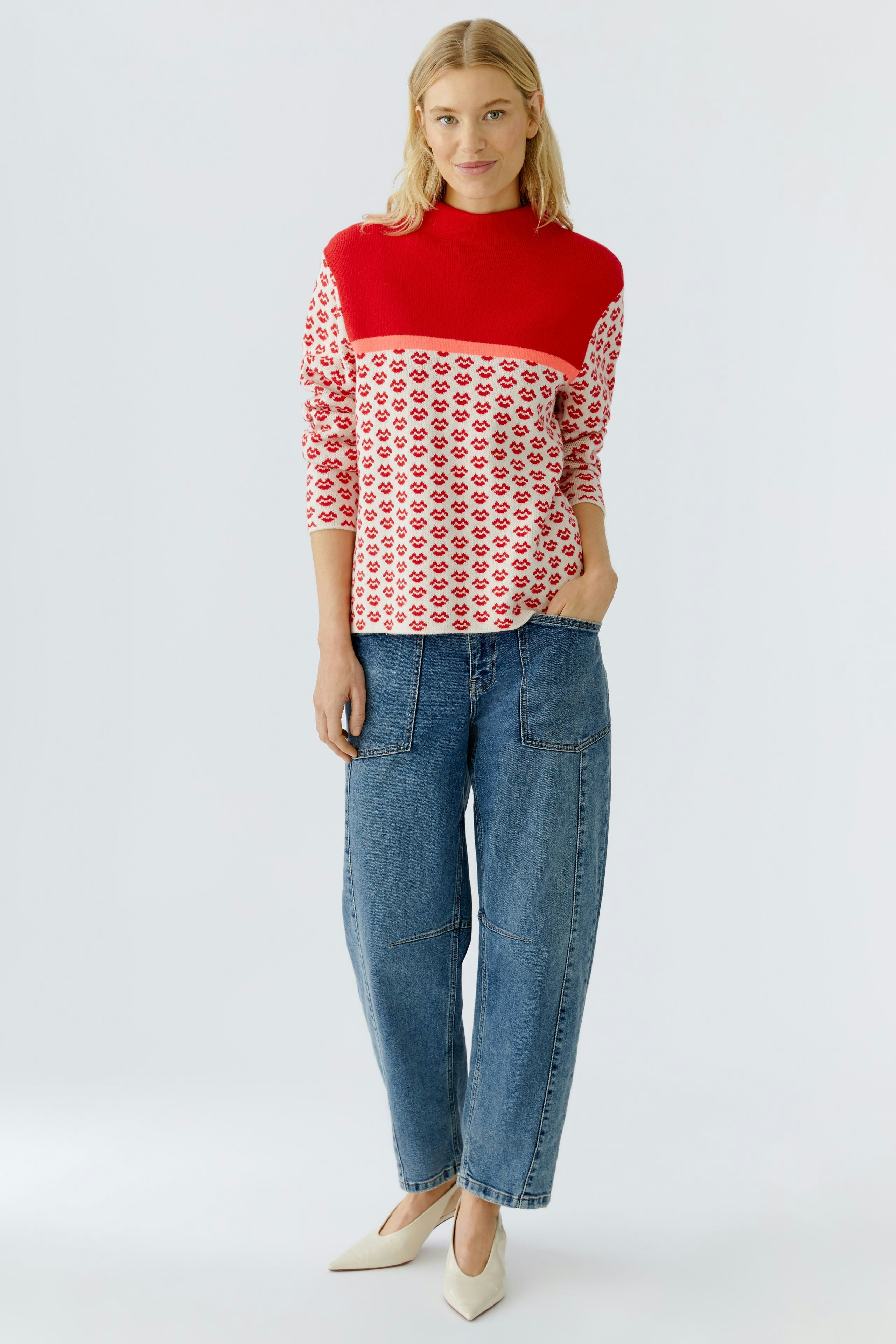 Casual women's pullover: A woman in a red and white patterned pullover paired with relaxed jeans.