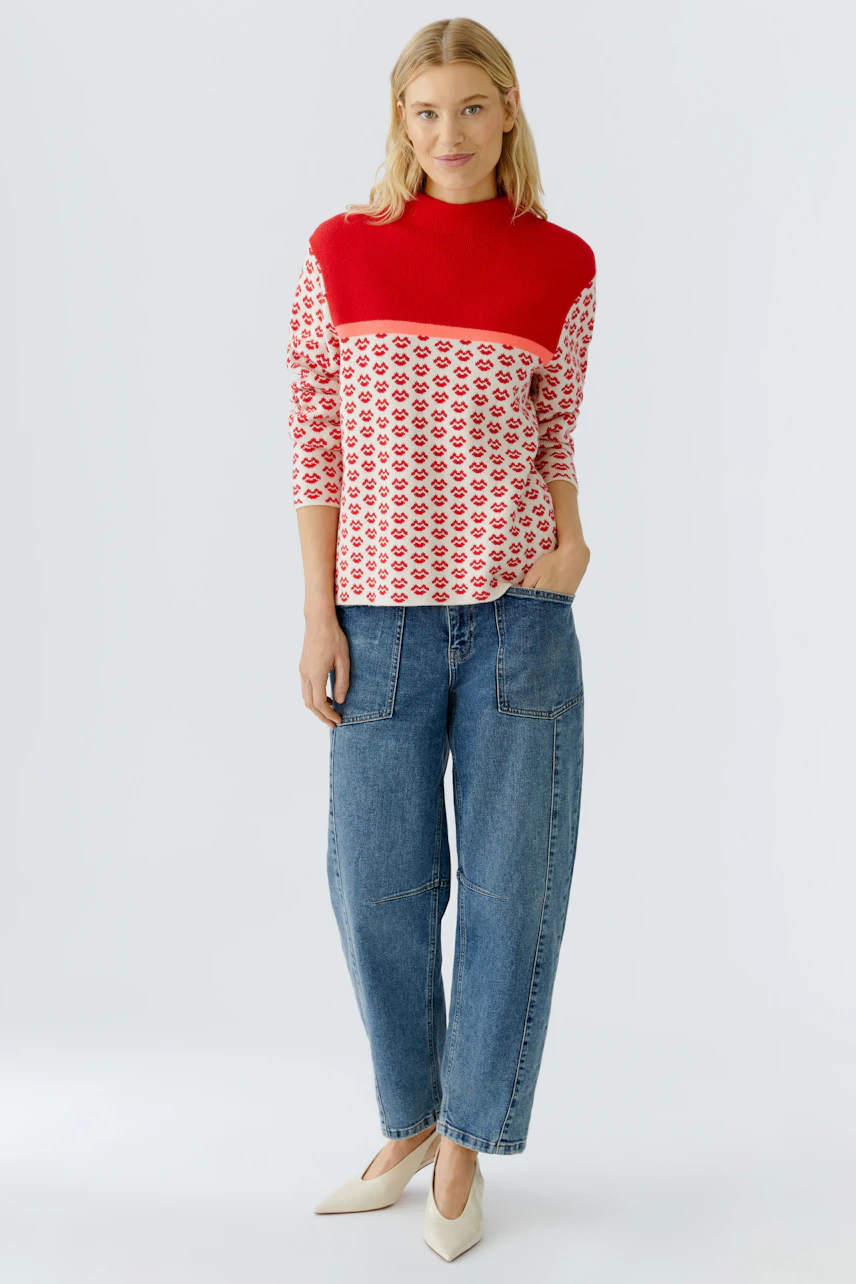 Casual women's pullover: A woman in a red and white patterned pullover paired with relaxed jeans.