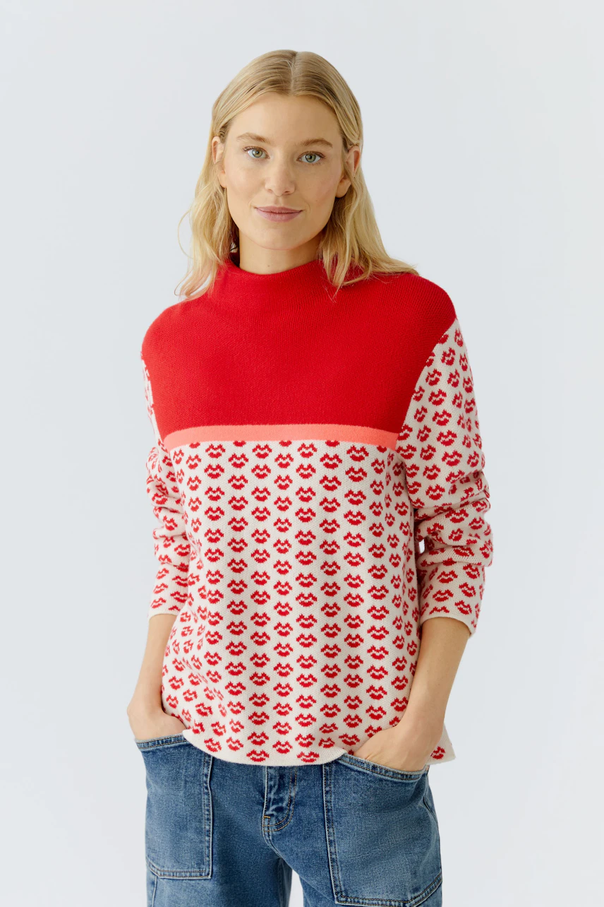Casual women's pullover: Young woman in a red and patterned pullover with a relaxed fit.